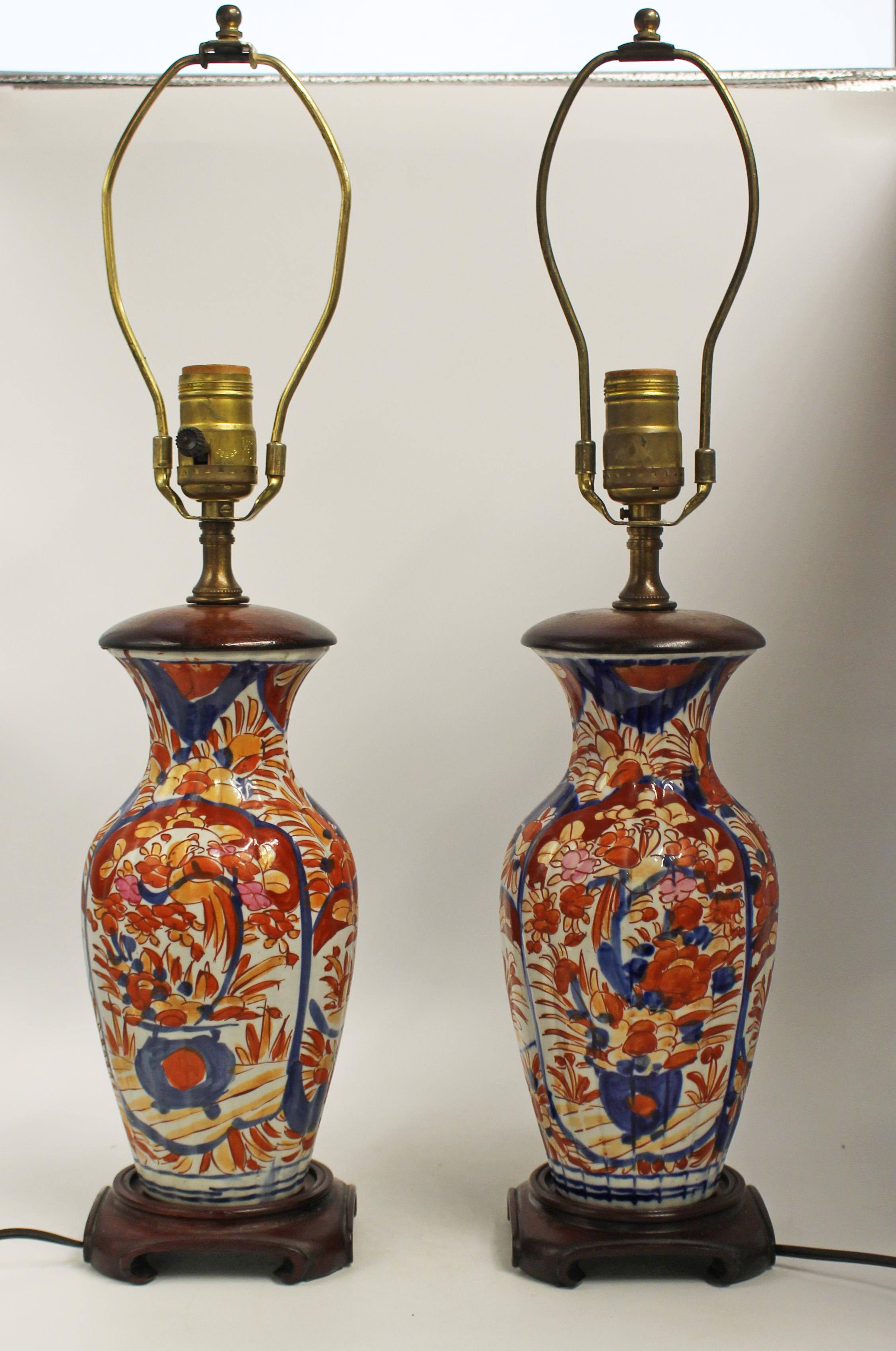 Circa 1860-80 pair of Japanese Imari vases mounted as lamps. Reeded bodies with large floral reserves with urns. Identical bodies decorated by 2 different artisans. Vases: 9.75