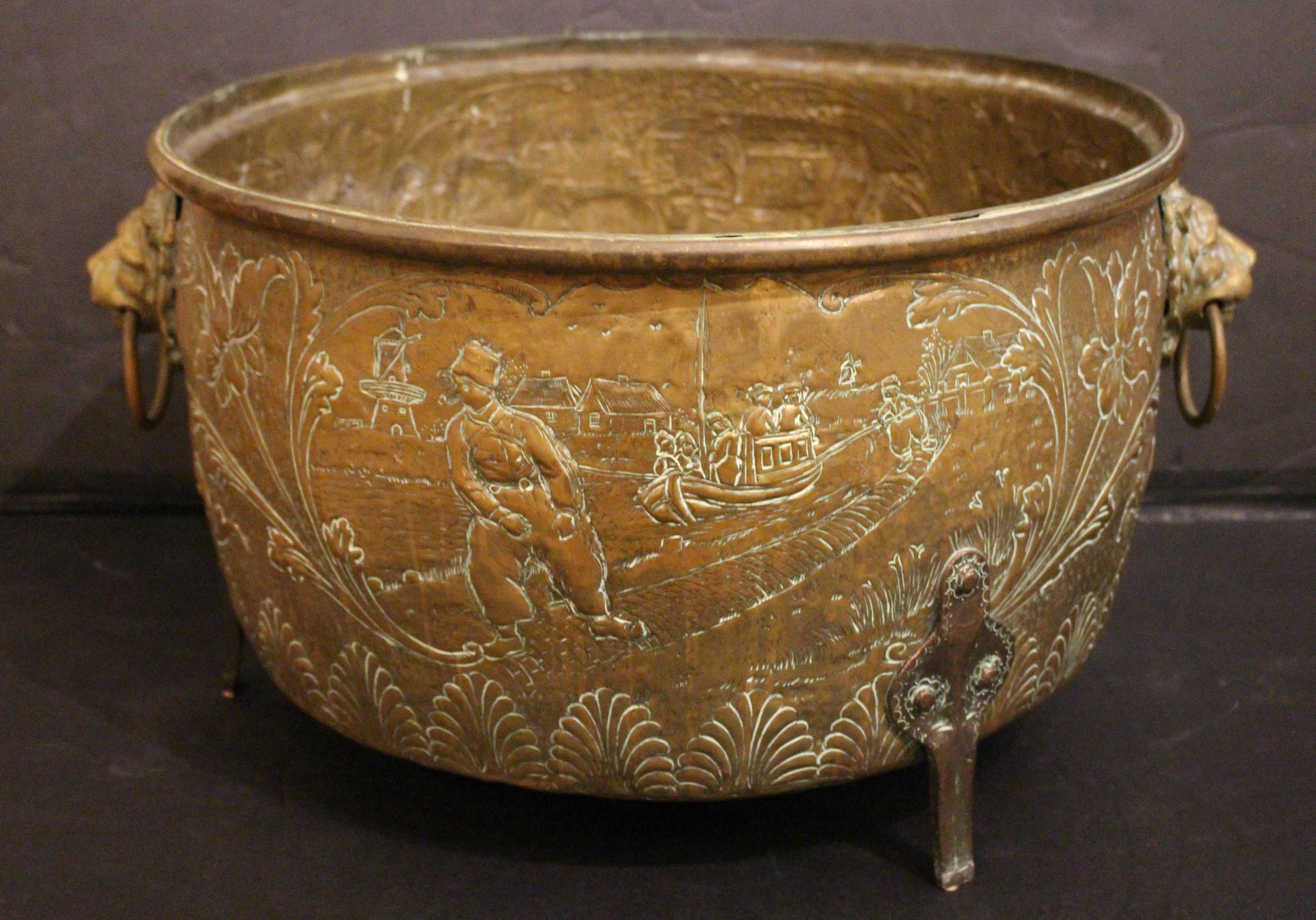 Giardino rotondo in ottone repousse del 1880 circa, olandese. Grande maschera di leone e maniglie ad anello. Si erge su piedi piatti e affusolati sormontati da un trifoglio in rame. Disegno in repousse di un bel cavallo da lavoro che traina una