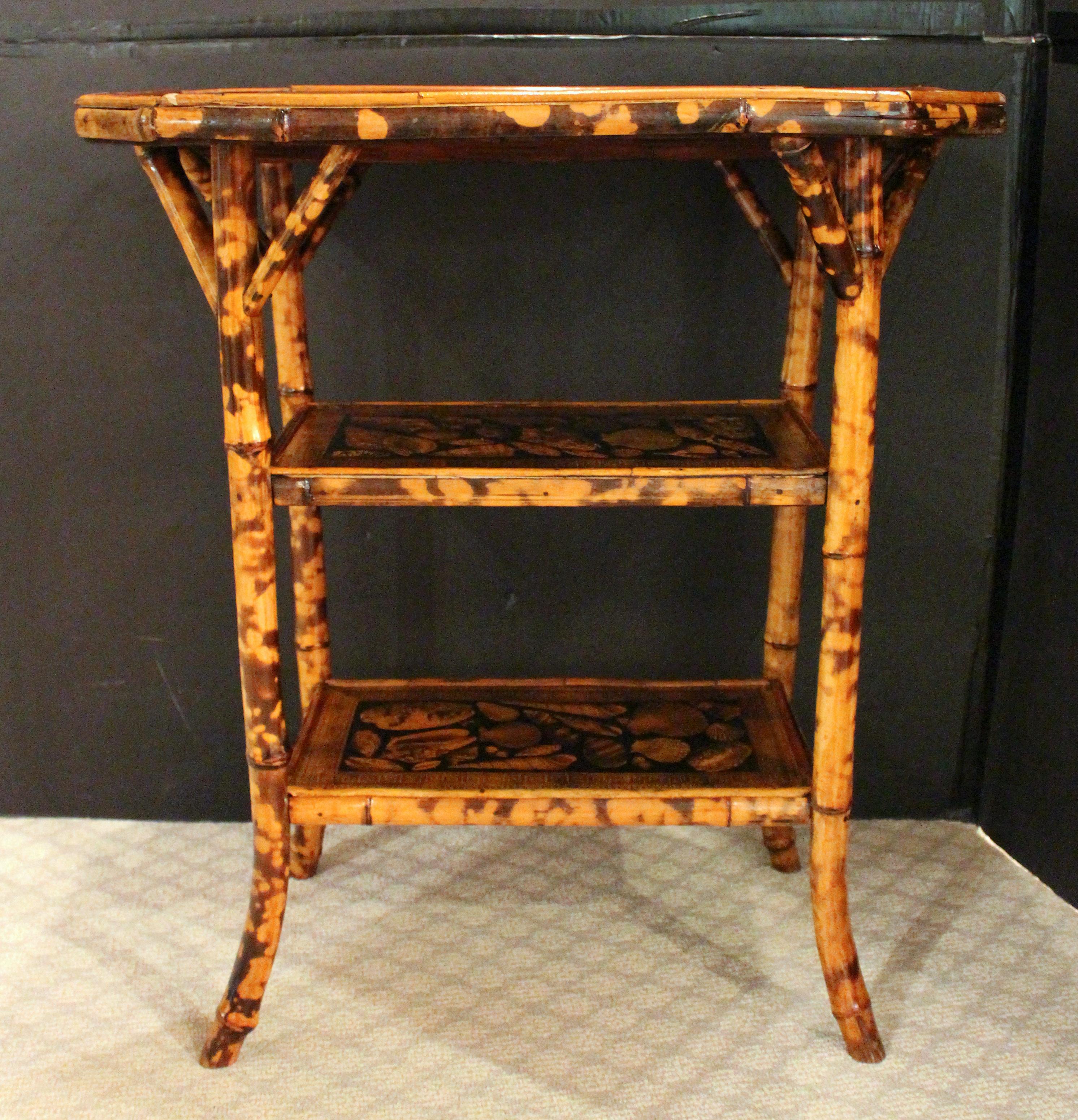 Circa 1880s English bamboo 3-tier side table. Large & handsome with elongated octagonal top, French slay feet & architectural strut supports. The surfaces now decoupaged with shells.
24.25