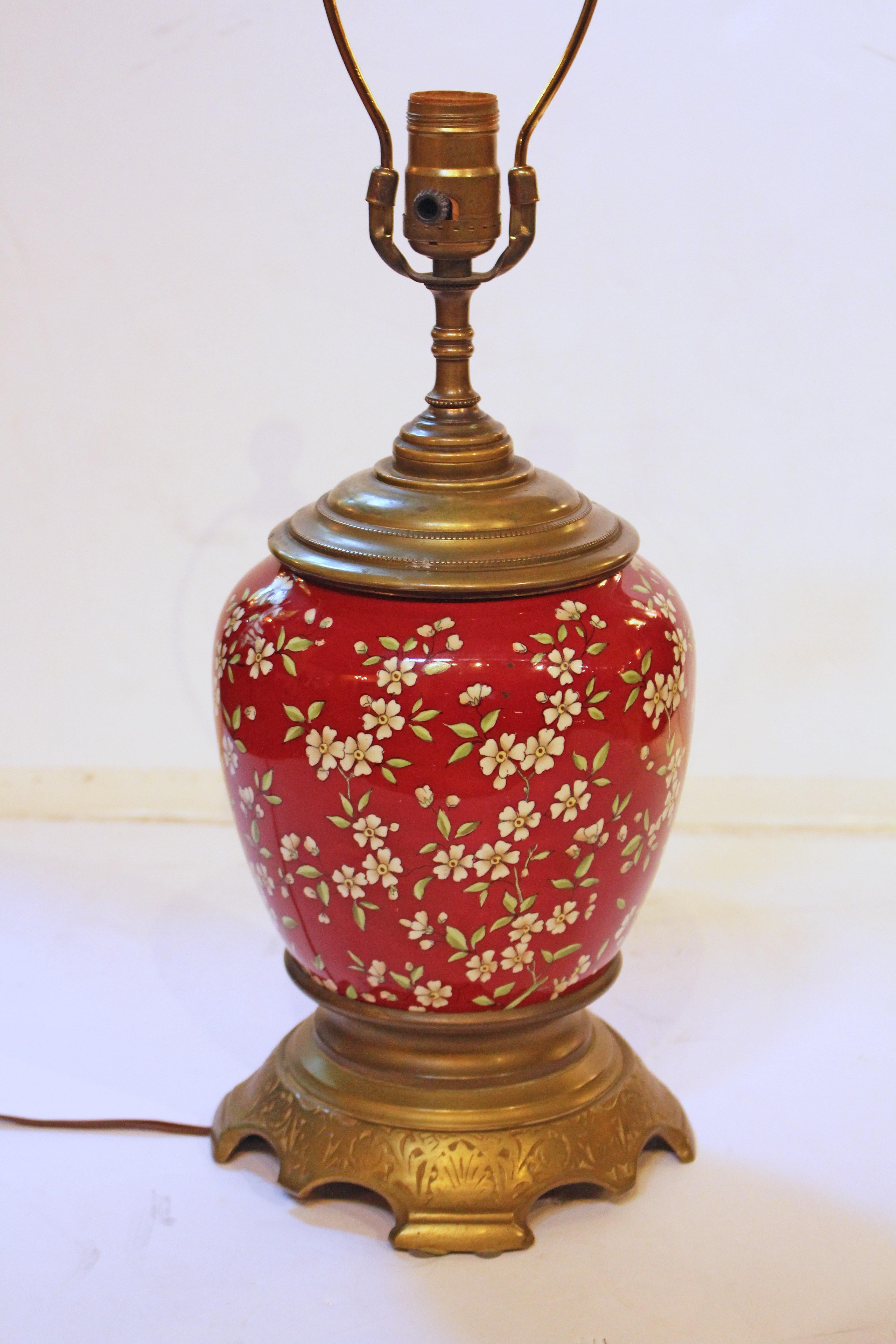 Circa 1880s Aesthetic movement electrified oil lamp base, likely English. Prunus decorated porcelain body with rich rose background; Aesthetic motif brass shaped, stepped foot base. Base with pads on two feet for stability. Antique, original stepped
