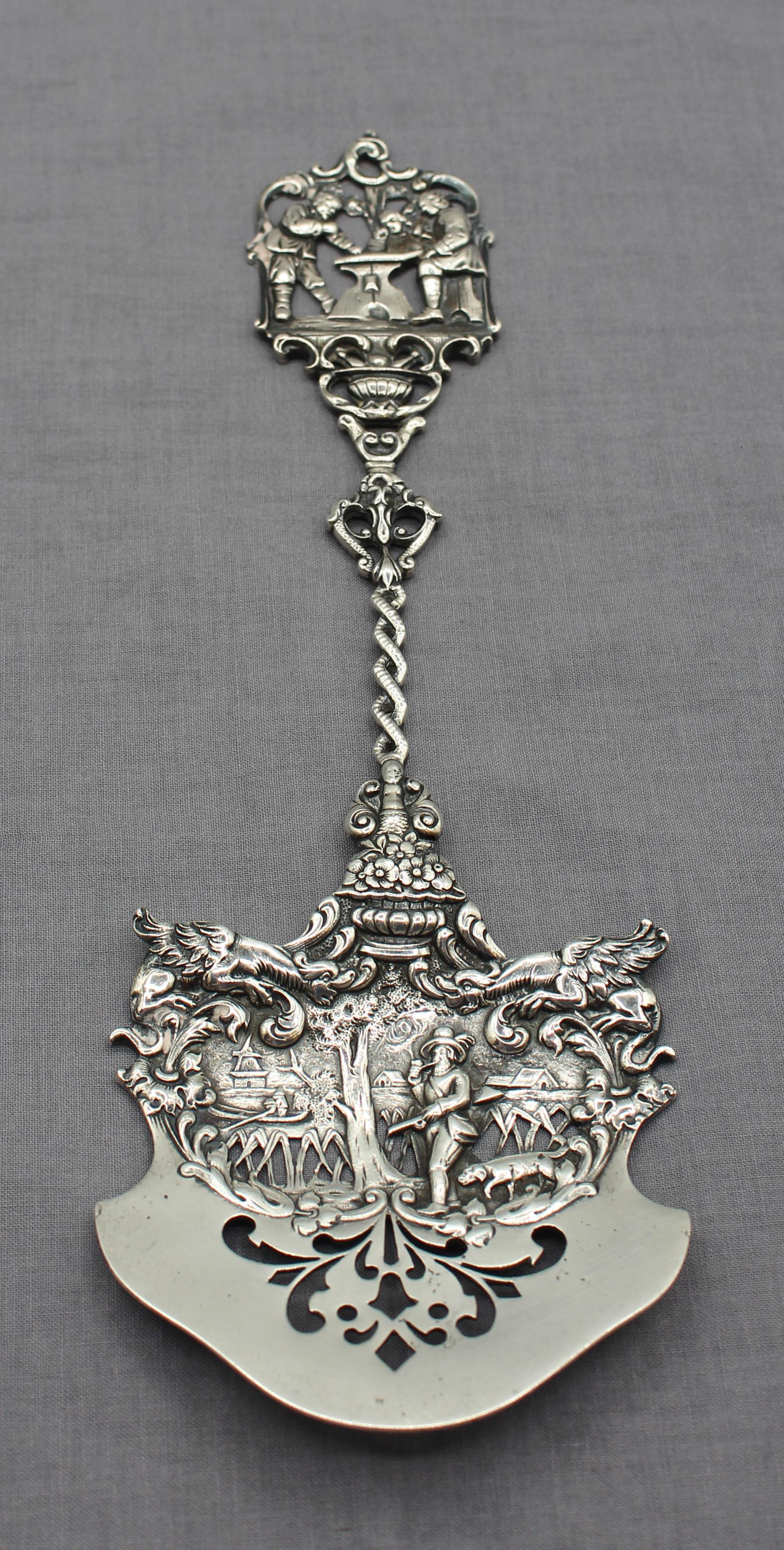 American Colonial Revival, c. 1885-1910, servidor calado de plata de ley. Estilo barroco con un cazador y un perro, un pueblo con un molino de viento y tres hombres ante una mesa de caballete del siglo XVII. Marcado: Marshall Field & Co, Sterling,