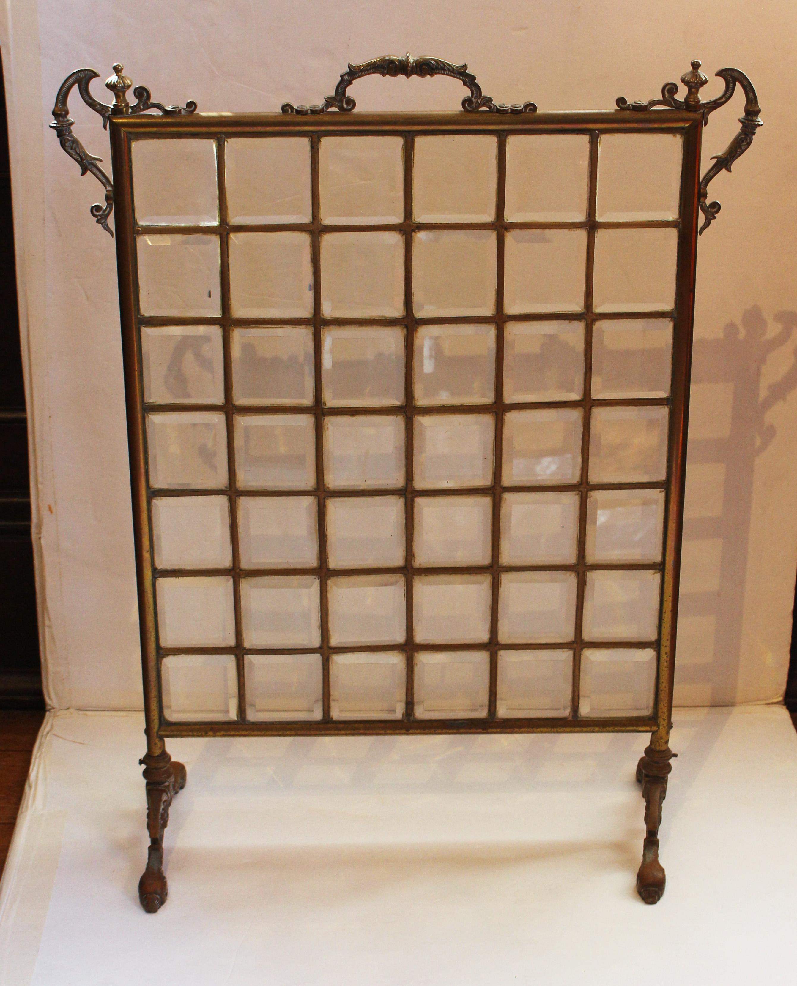Circa 1900 beveled glass & brass fireplace screen, American or English. Forty-two beveled glass panels set in brass channels contained in ornate, cast & tubular brass frame.
23.5