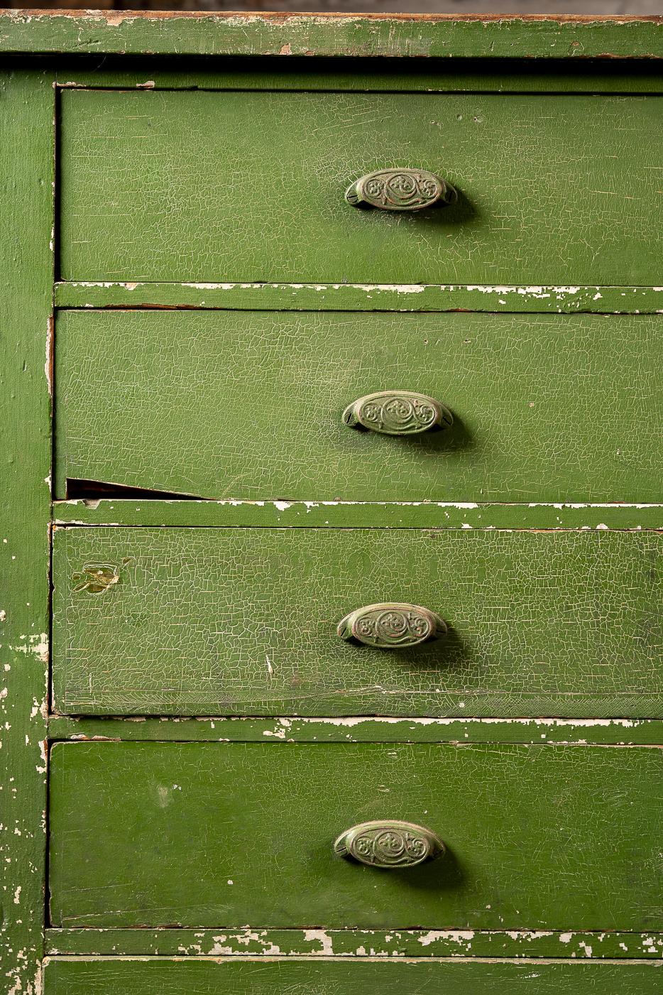 This large countertop cabinet was used for decades in a ship foundry in Milwaukee, WI housing a number of schematics and tools. The cabinet boasts ten drawers and has an industrial green painted finish. This cabinet has seen much use over the years