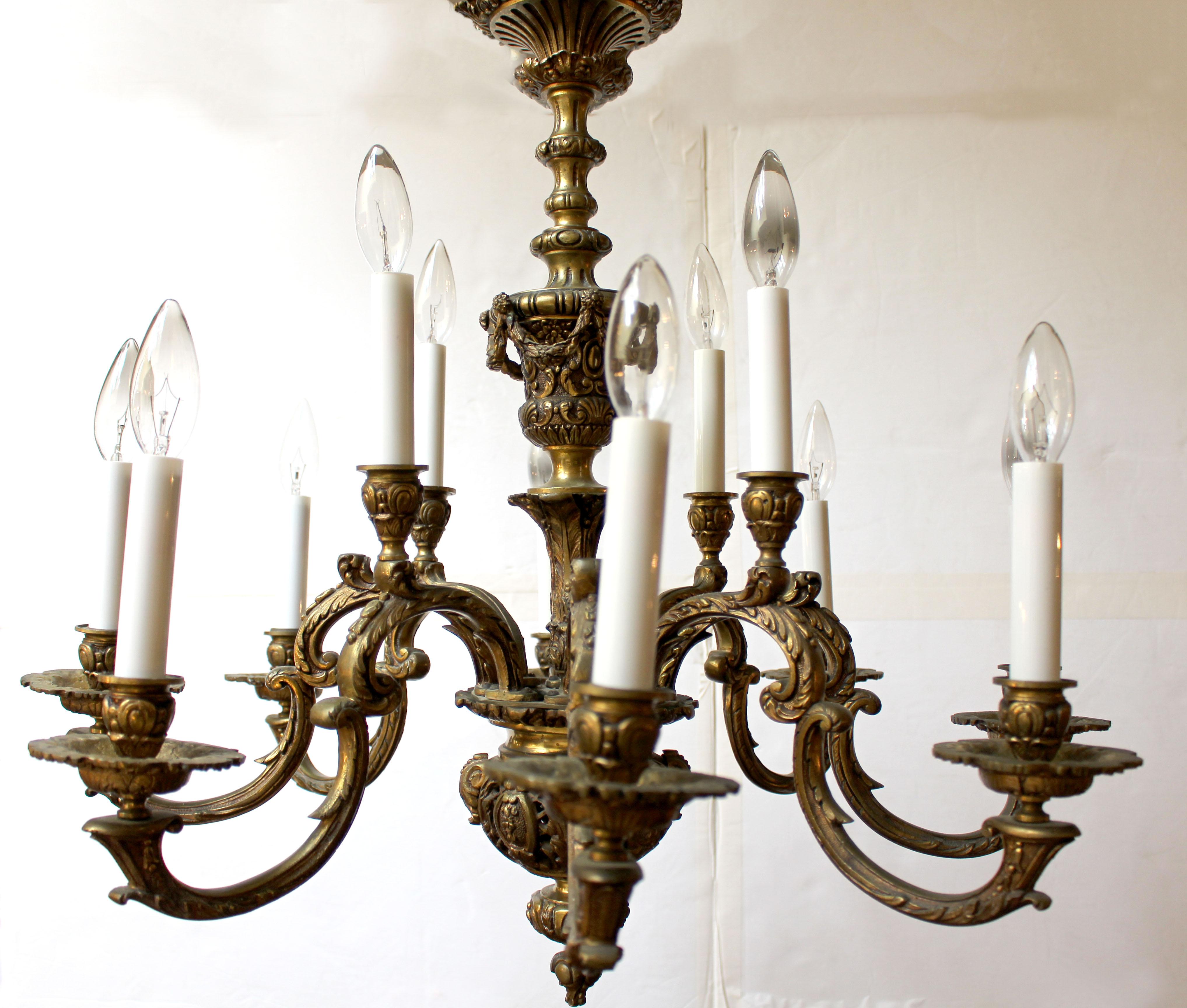 Circa 1900 French cast bronze 12-light chandelier, Louis XIV style. Baroque influence C-scroll based form, the whole decorated with floret, acanthus leaves & bellflowers. Robustly decorated central swagged urn. Includes a ceiling canopy.
Approx.