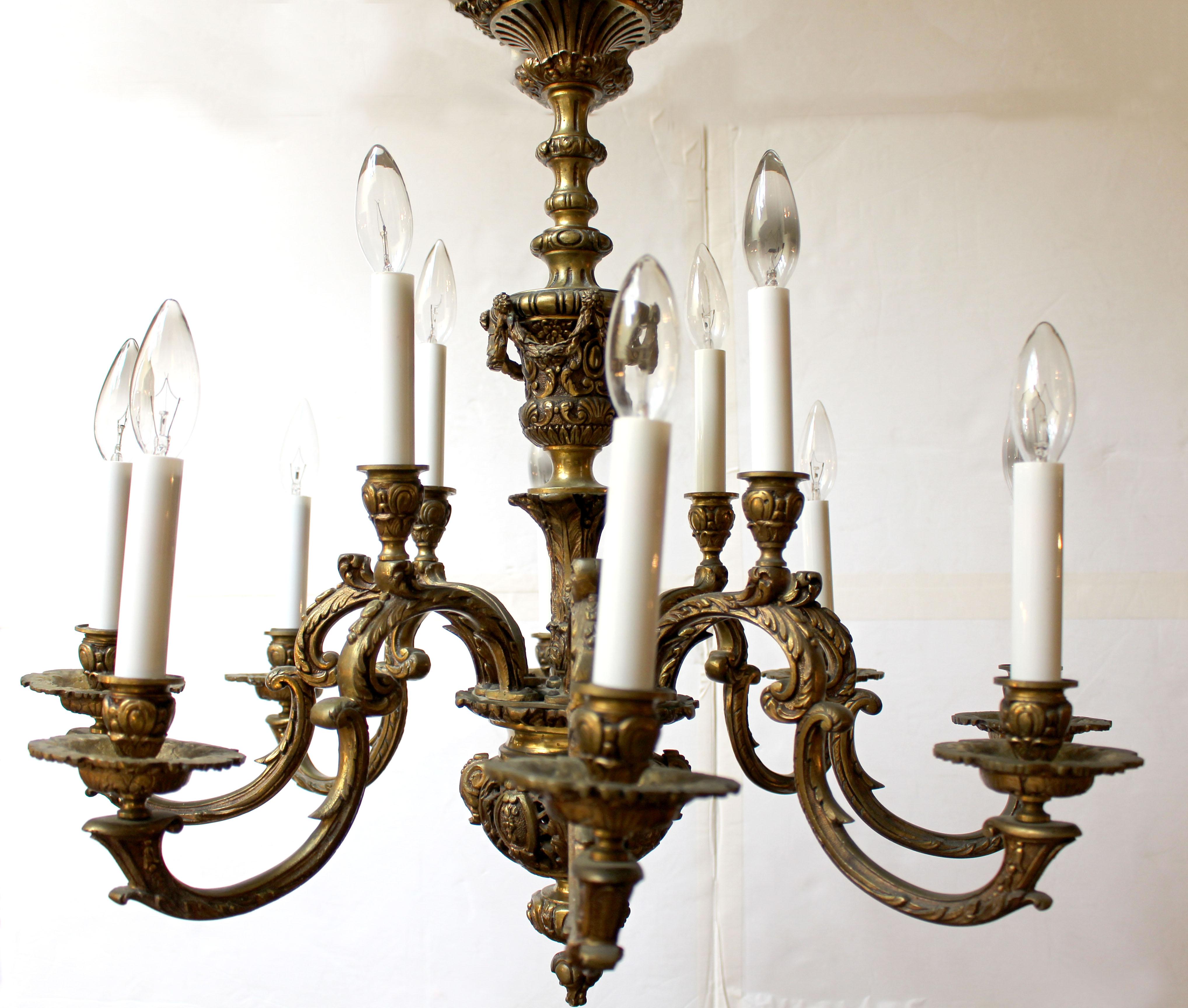 Lampadario a 12 luci in bronzo fuso francese del 1900 circa, stile Luigi XIV. Forma a C con influenza barocca, il tutto decorato con fiori, foglie d'acanto e campanule. Urna centrale decorata in modo robusto e con un motivo a scacchiera. Include un