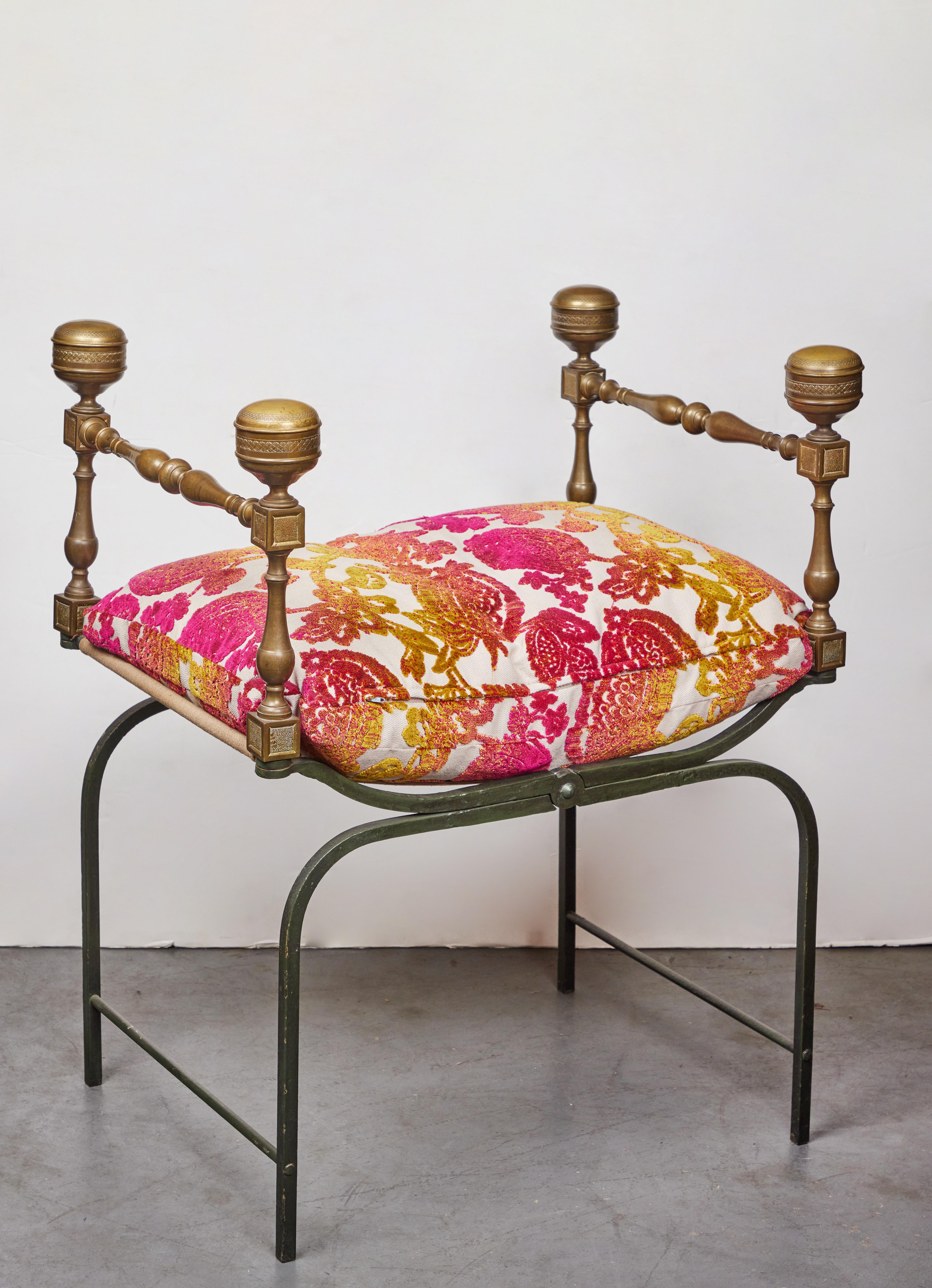 A turn-of-the-century, forged iron, Savonarola chair featuring incised brass arms above turned stretchers capped by four, large finials. Finished with a contemporary, hand-sewn tuft in vibrant, contemporary silk velvet upholstery that sits on the