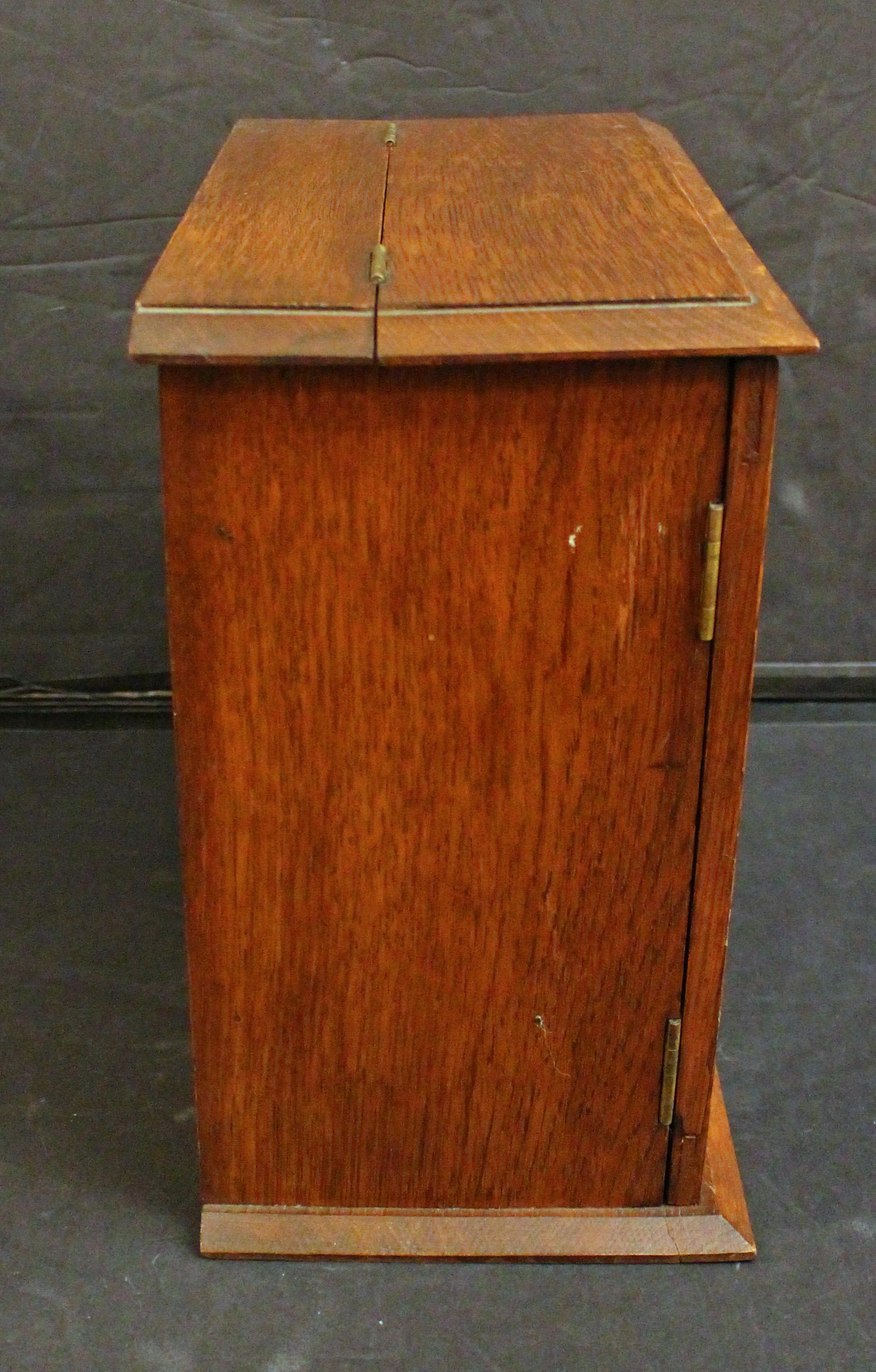 Gabinete de fumador de sobremesa de la época eduardiana inglesa, circa 1910. En buen estado general. Roble con paneles de puerta de cristal biselado. Equipado para cuatro pipas, una tabaquera y dos cajones con tiradores de marfil. La parte superior