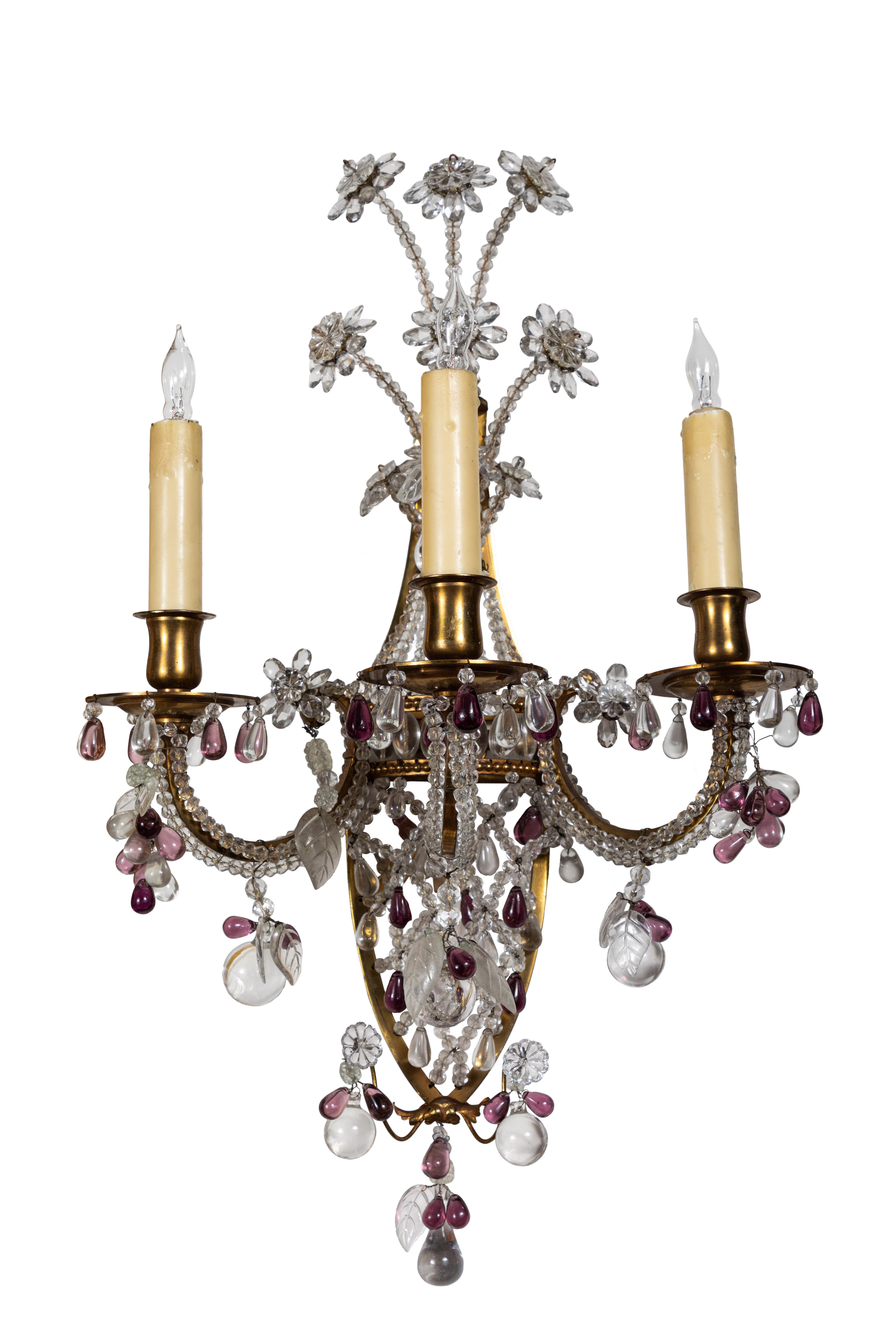 Beautiful pair of three arm, gilt bronze and crystal sconces each crowned with a spray of flowers. The arms hand beaded, and the whole of each embellished with fruit form drops, both clear and in amethyst-colored crystal. Newly wired for U.S.