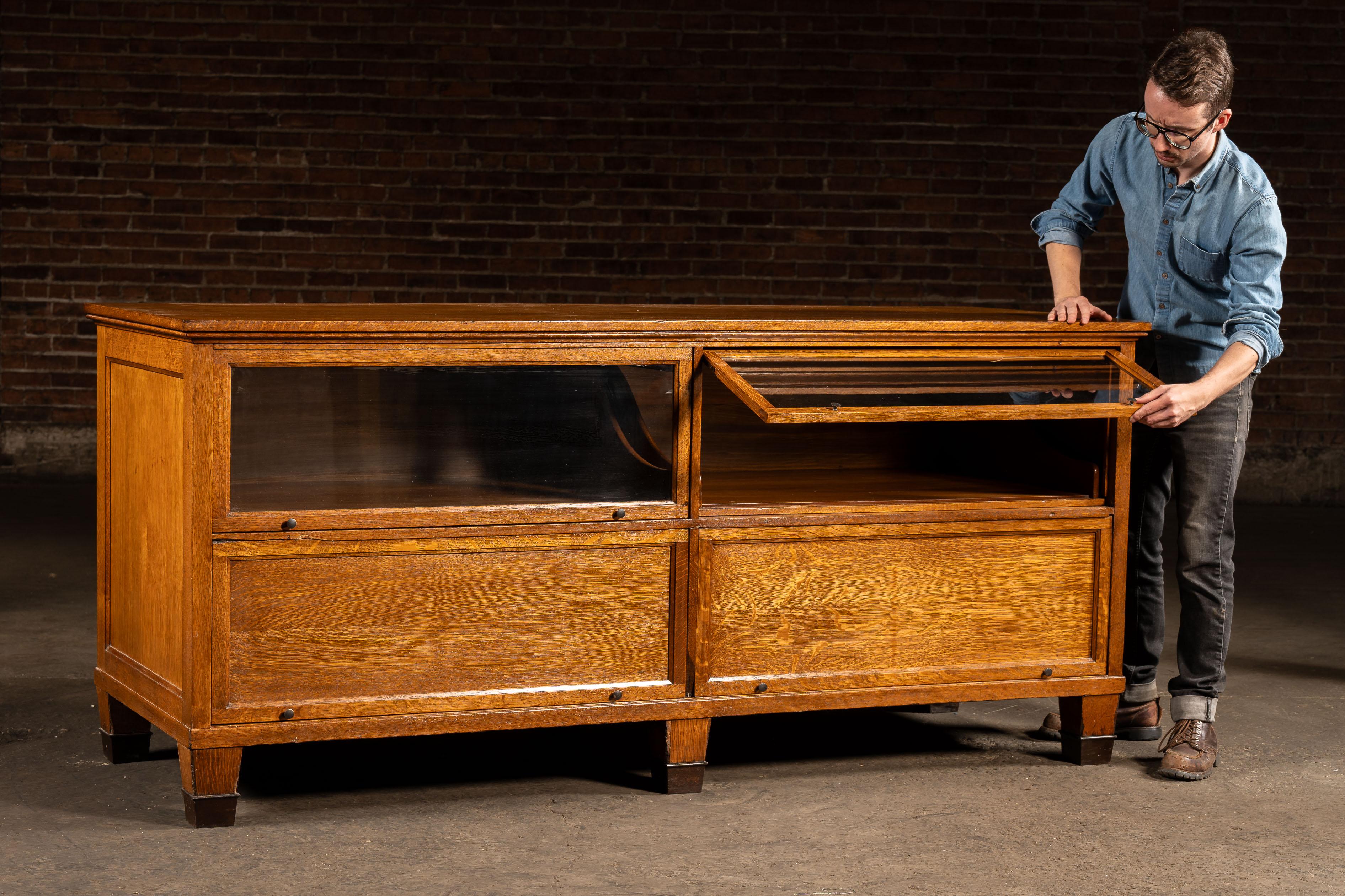 Un mobile a isola realizzato con bellissimi pannelli segati a quarto di dollaro con ante in vetro e legno in stile barrister.

Questo mobile vanta quattro cassetti scorrevoli, due sopra e due sotto. Le guide per cassetti in ottone sono integrate