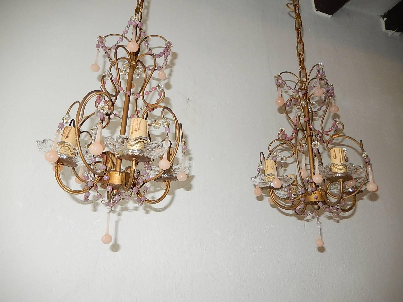 Beautiful rare chandeliers, circa 1920. Chandelier housing four lights sitting in crystal bobeches. Rewired and ready to hang! Gold gilt metal. Macaroni swags of opaline beads. Adorning small pink opaline drops, not missing one. Adding 12 inches of