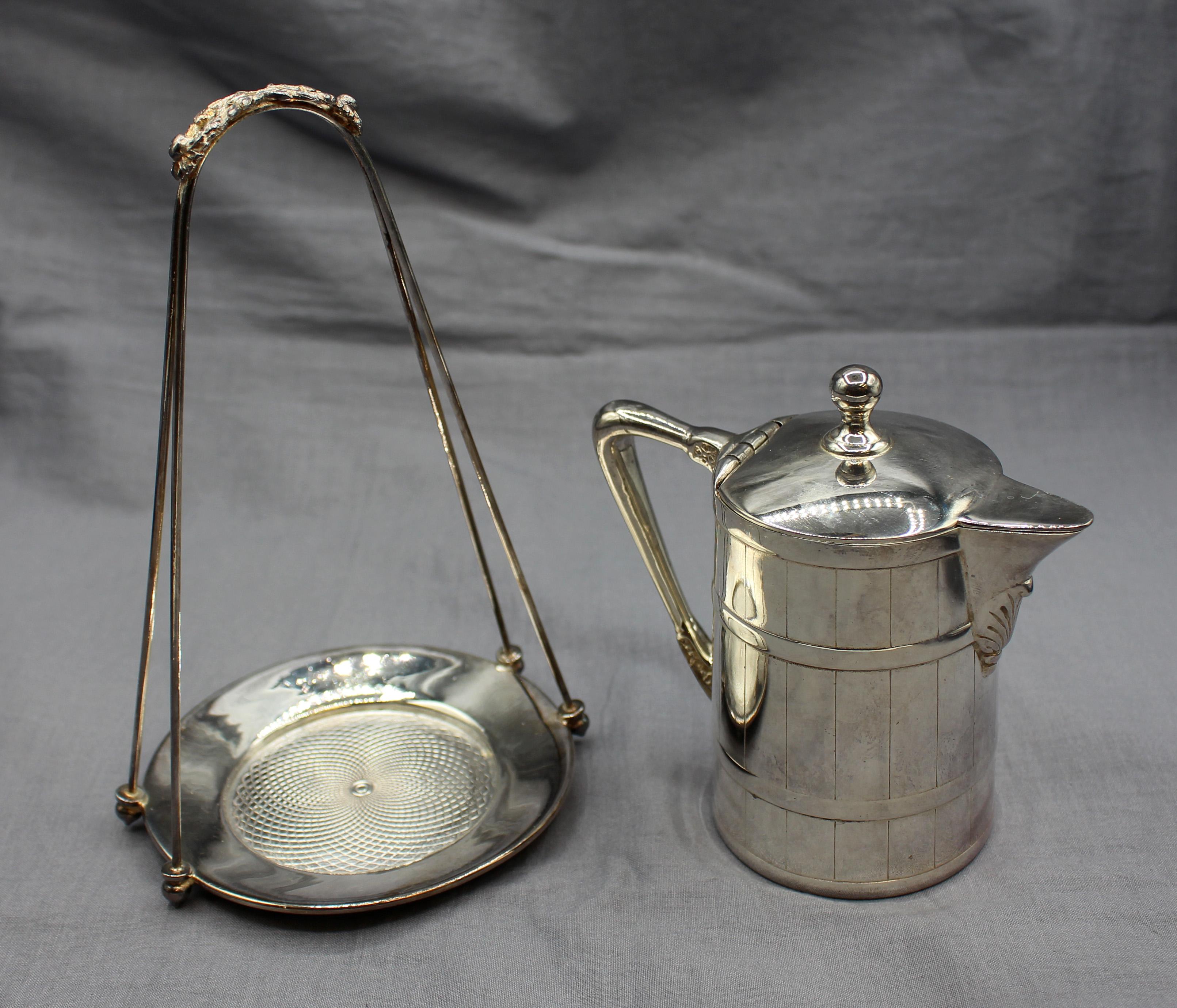 Brocca da sciroppo in argento del 1920 circa con supporto, Anglo-Americana. Progettato in modo da imitare una brocca di legno legata e dogata. Sostituito alla fine del XX secolo. 