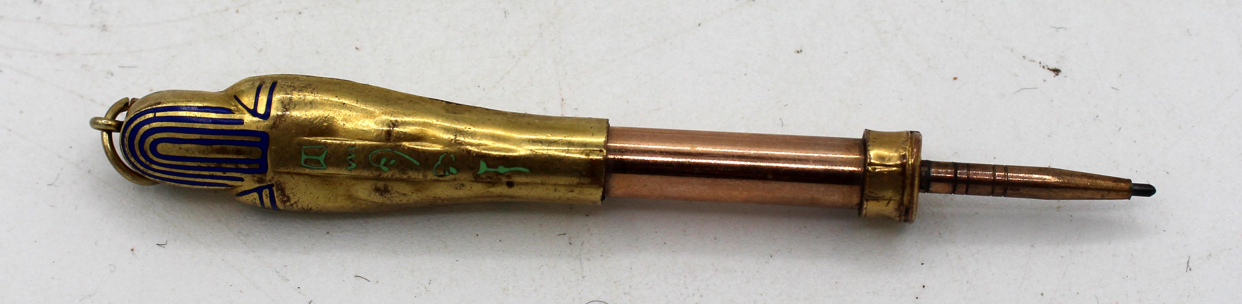 Circa 1920s mummy sarcophagus form pendant retractable pencil, likely Continental. Gilt & enamel on silver or white metal. The discovery in 1922 of King Tut's tomb set off a rage for all things Egyptian, especially mummy objects. Illegible marks on