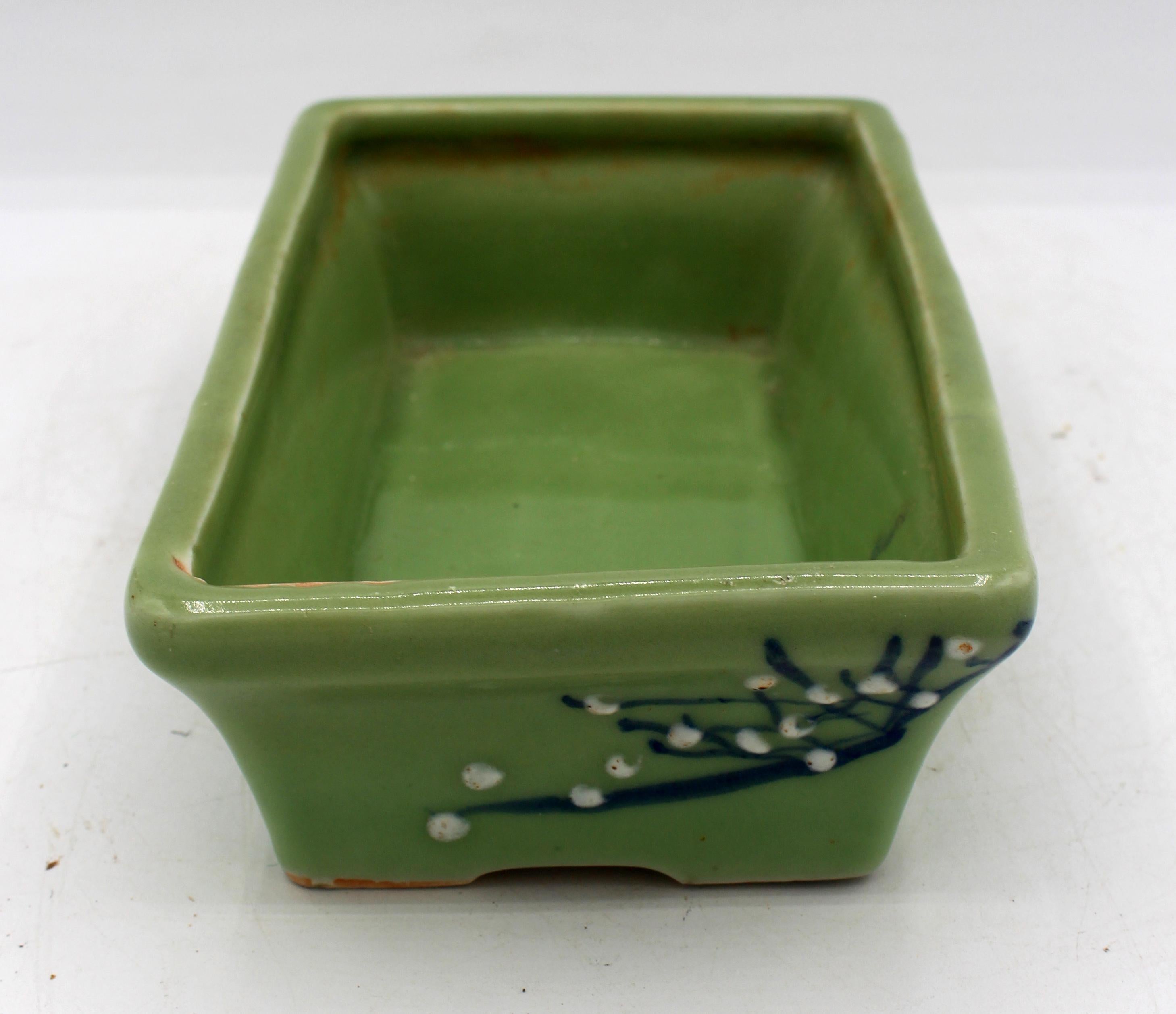 Circa 1930 Japanese porcelain bonsai pot, celadon ground. Blue underglaze branches & white pâte-sur-pâte blossoms.
7 5/8