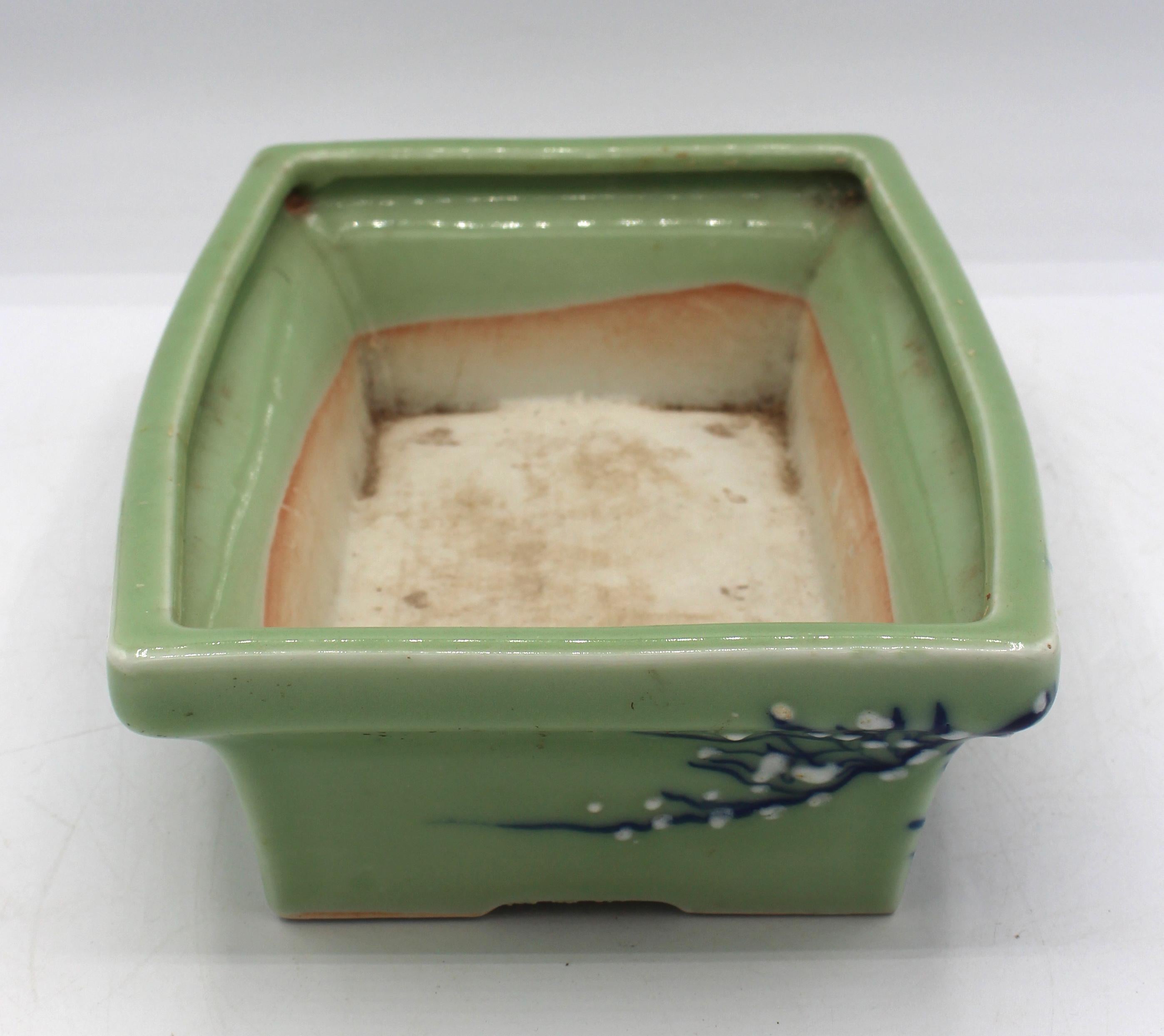 Circa 1930 Japanese porcelain bonsai pot, celadon. Blue underglaze branches & white pâte-sur-pâte blossoms. Chip under one foot.
9.5
