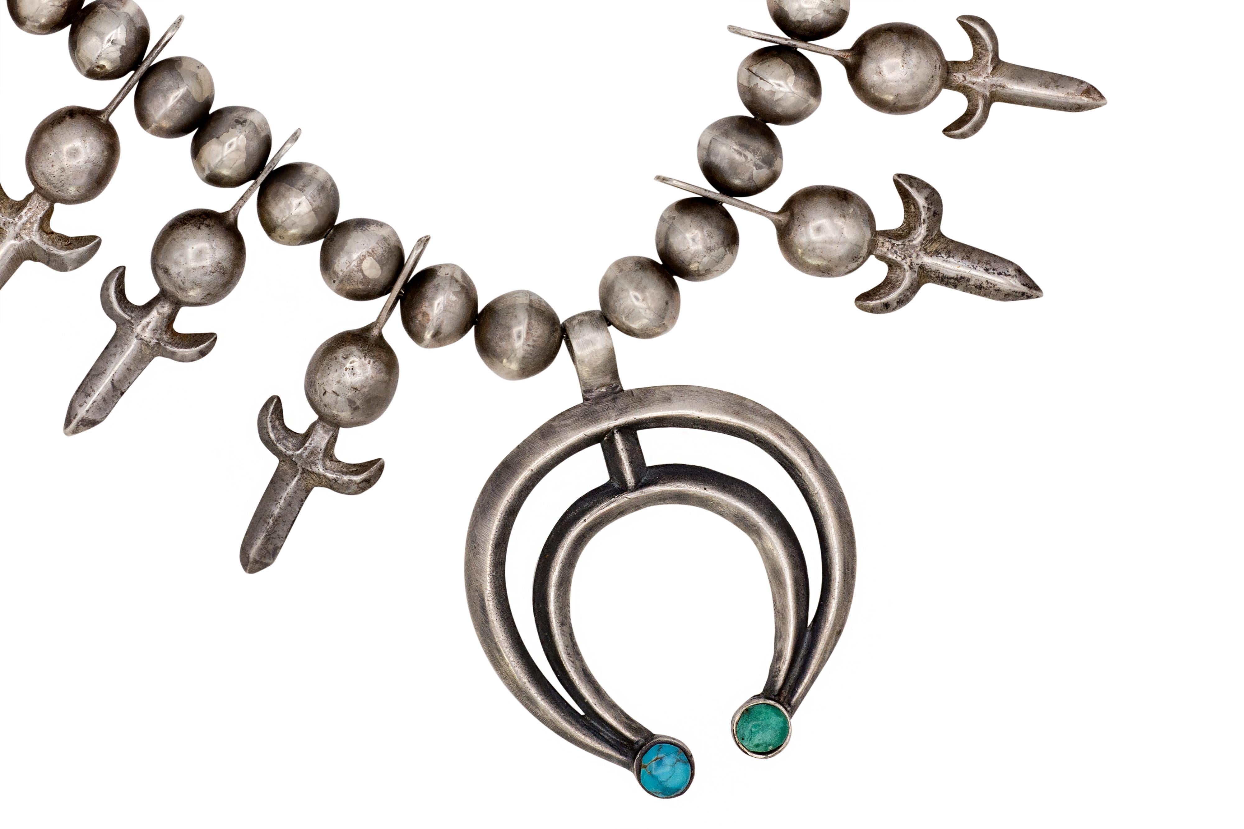 A historic turquoise and sterling silver Fleur-de-Lis squash blossom necklace, Navajo, c. 1940. 
The necklace is 22.75