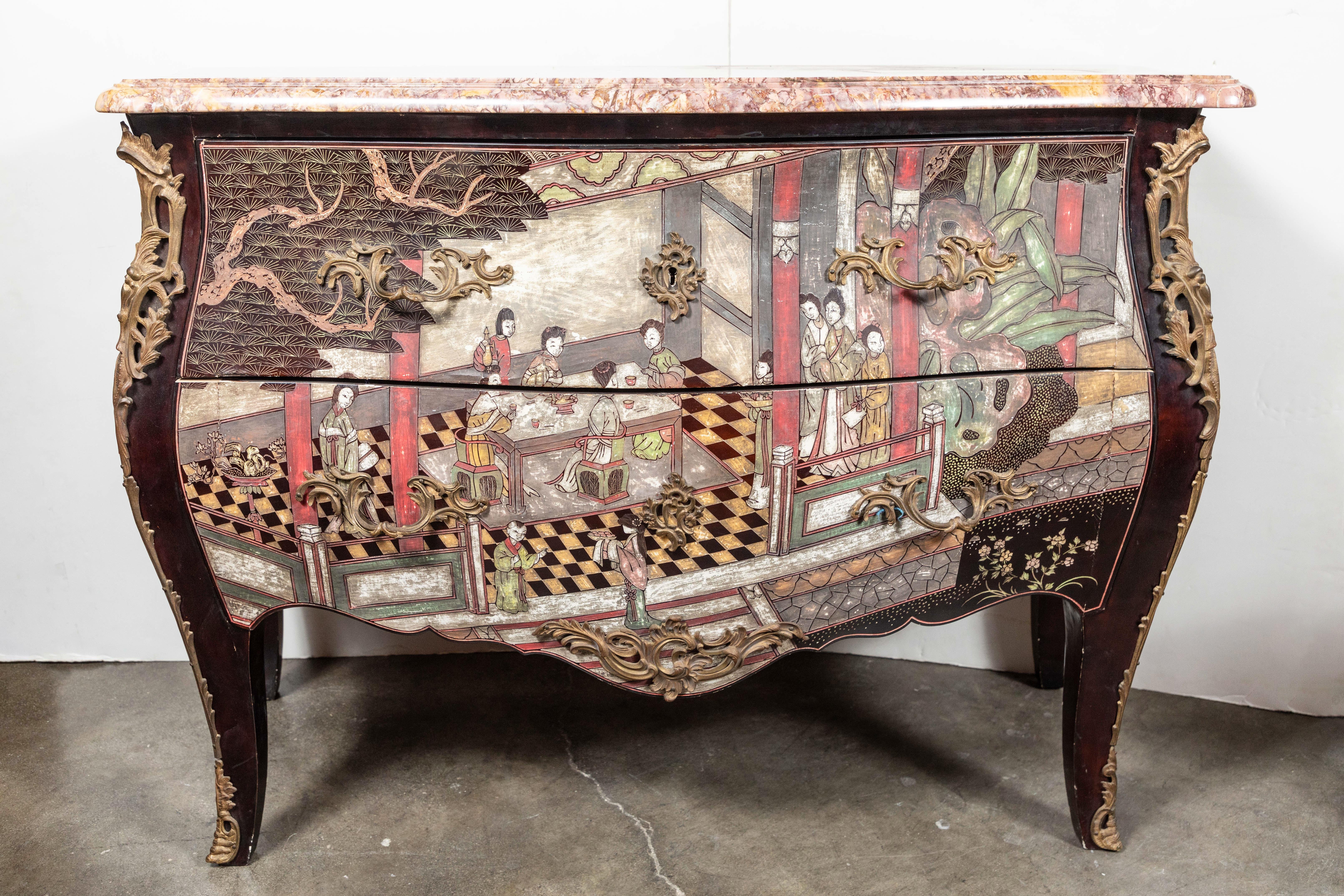 Absolutely charming, two-drawer, bombe-form, midcentury, Coromandel style, Chinoiserie commode in black lacquer, featuring a colorful scene of figures in an interior. Embellished with gilt bronze mounts, escutcheons, and drawer pulls. Surmounted by