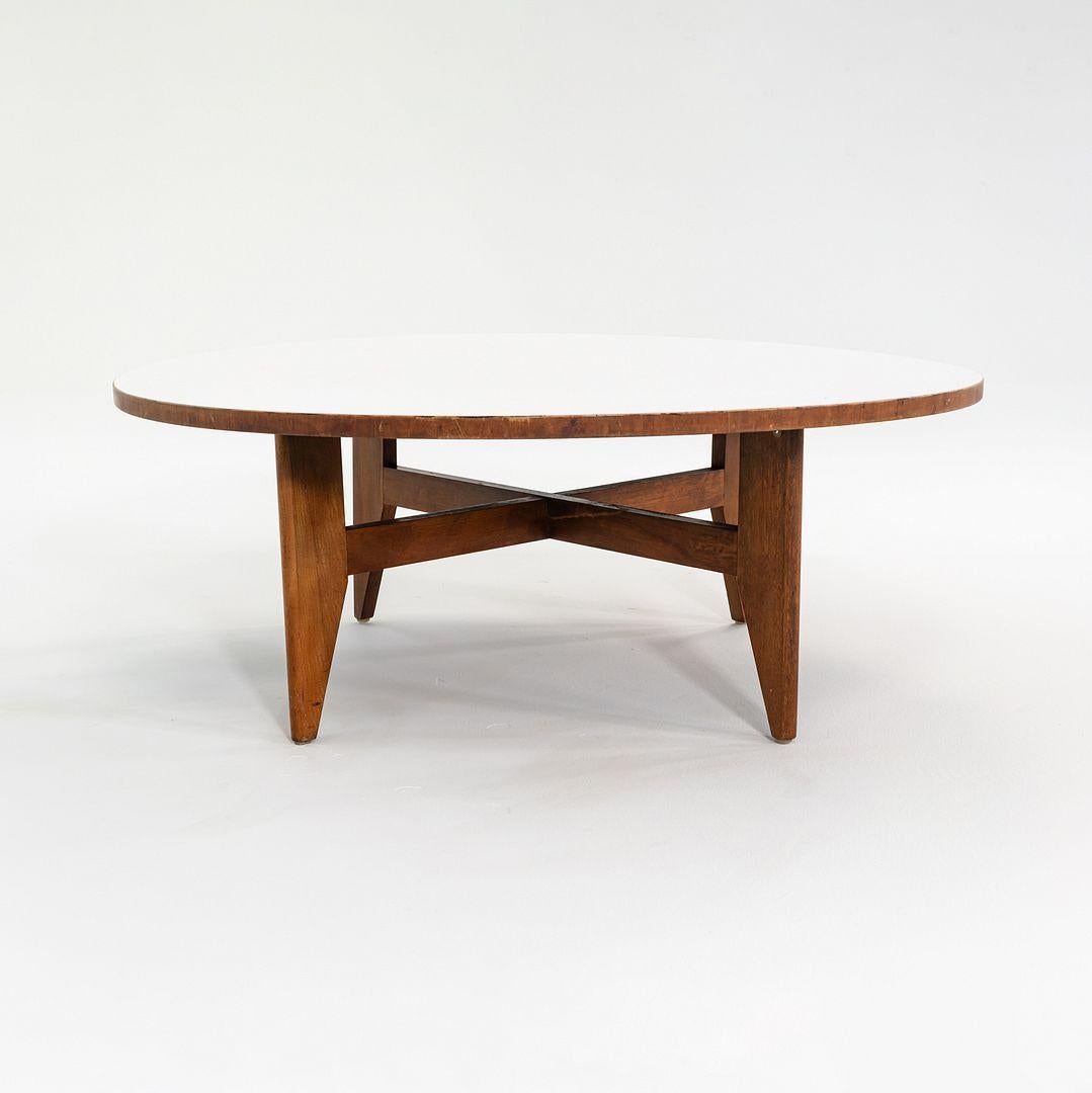 Il s'agit d'une table basse circulaire, modèle 5059, initialement conçue par George Nelson pour Herman Miller en 1946. Cet exemplaire date d'environ 1952. Le design comprend une base en X en bois brun avec un plateau rond en stratifié blanc. 
 
 La