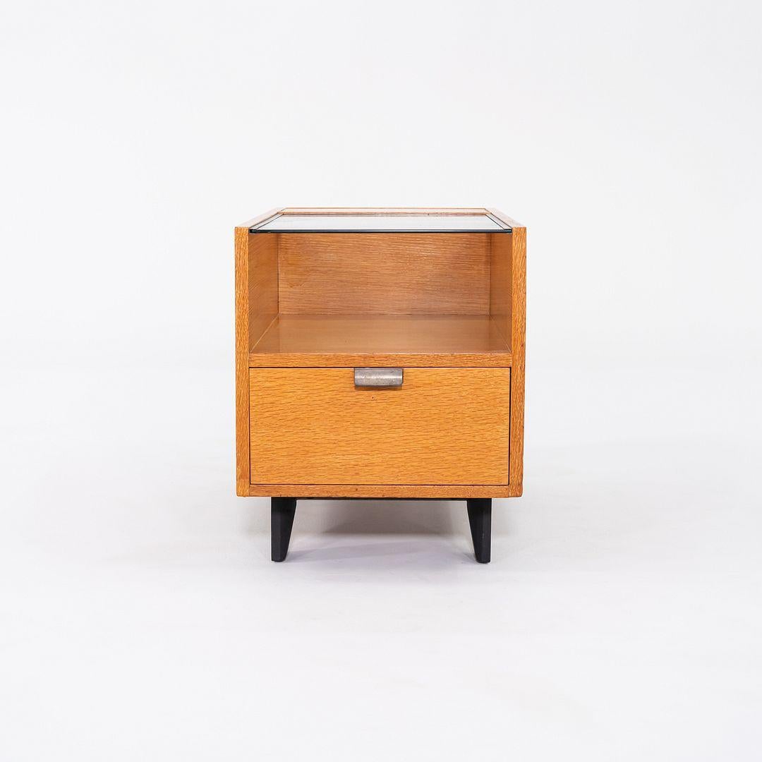 Il s'agit d'une table d'appoint/armoire de la série Basic Cabinet de George Nelson, conçue à l'origine en 1946. Cet exemple particulier a été produit par Herman Miller C.I.C. 1954. Cette pièce est composée d'un cadre en noyer, d'un plateau en verre
