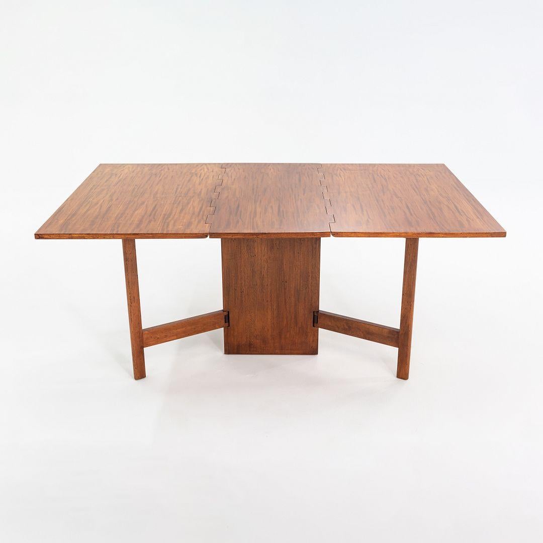 Se trata de una mesa de comedor Gate-leg, modelo 4656, diseñada por George Nelson para Herman Miller en 1946. Esta pieza data de 1954 y está construida en caoba. Tiene una amplia bisagra de madera y una pata de doble reja para asegurar la