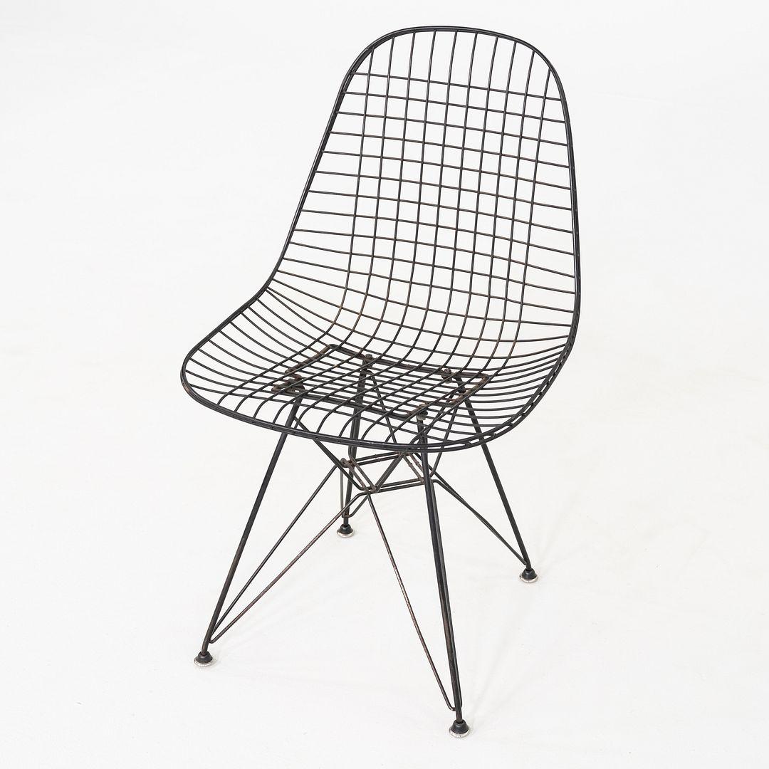 This is a pair of DKR Wire Dining Chairs, originally designed by Charles and Ray Eames in 1951. These particular examples were produced by Herman Miller circa 1956. The pair features wire seats atop Eiffel bases in black coated steel. DKR is an