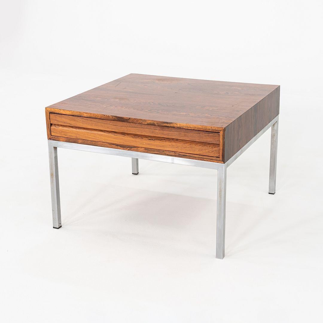 This is a Rosewood Side or End Table, having a square chromed-steel base and a working drawer. The piece was produced by hand in Denmark. The grain pattern of the rosewood veneer is exquisite, and the piece is solidly built.
  
 This table measures