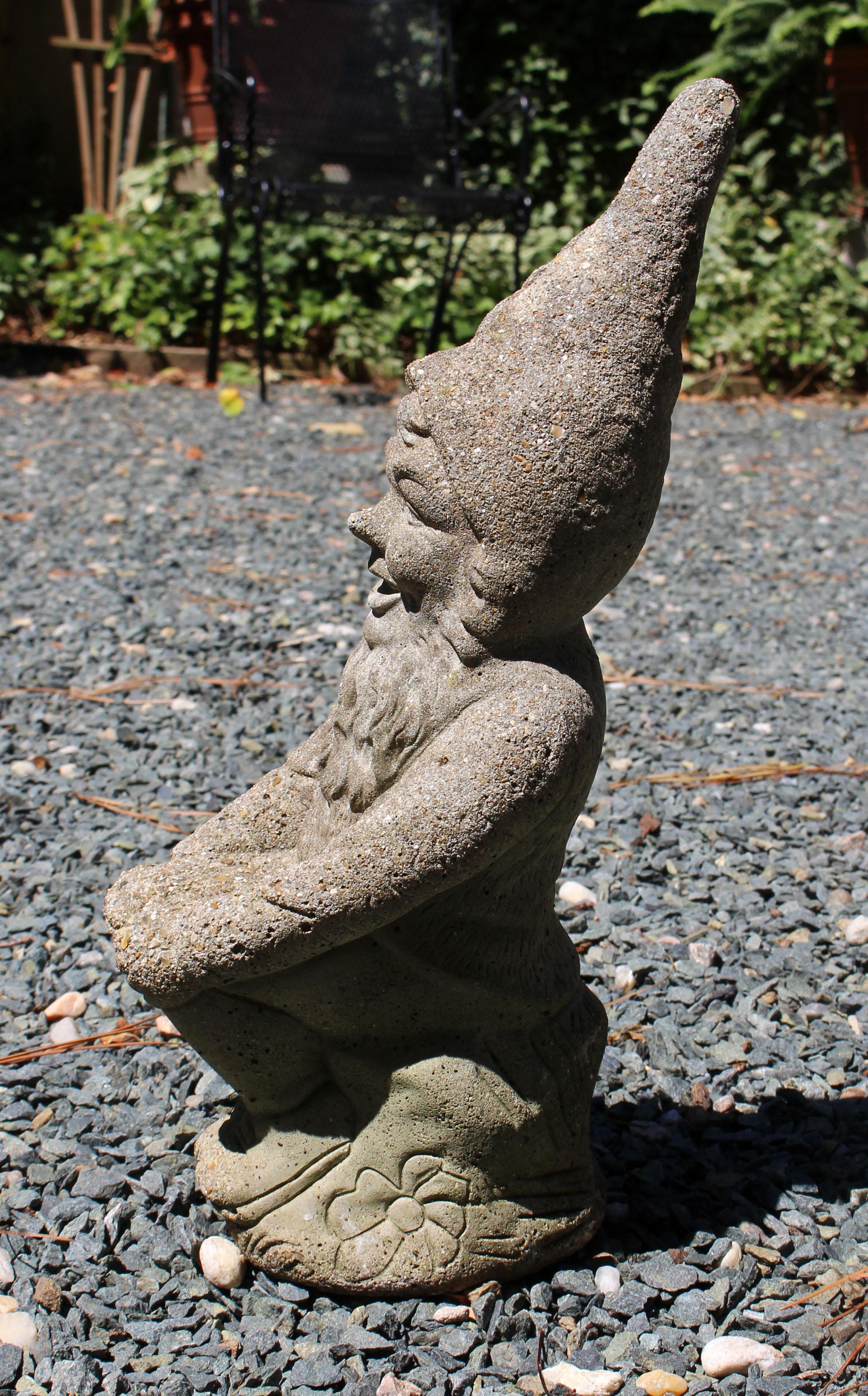 Circa 1960s cast stone garden gnome, English. Sitting on a stump with his hands on his knees - charming face, long beard & pointed cap. Tiny toadstool by his feet; impressed decoration to create the 