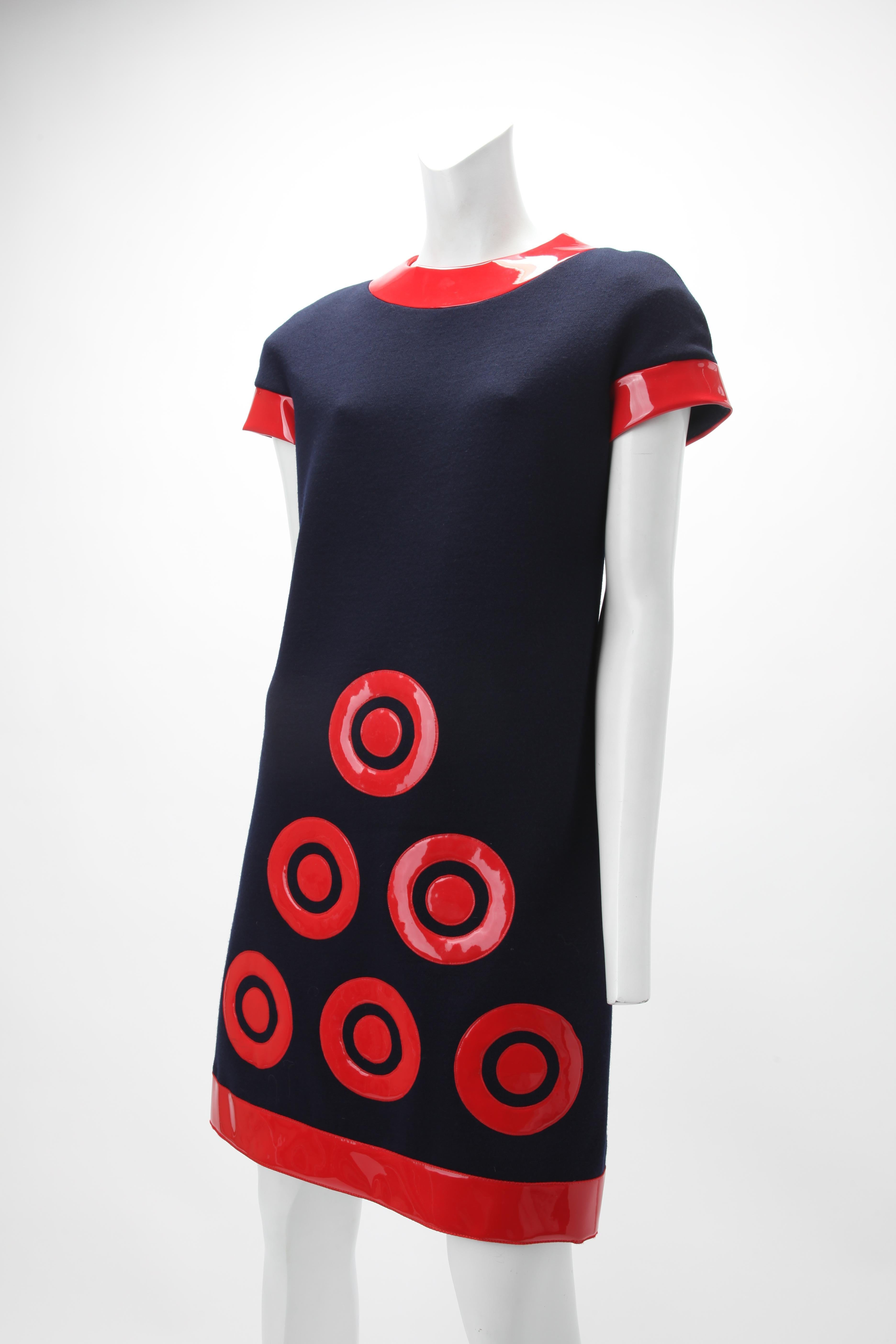 c. 1967 Pierre Cardin Futuristic Dress
Mini dress of navy wool jersey knit. The tubular mini dress has a rounded neckline and short sleeves. Red, shiny vinyl trim at neckline, sleeve hem, lower hem, and in the form of six Pierre Cardin bullseye