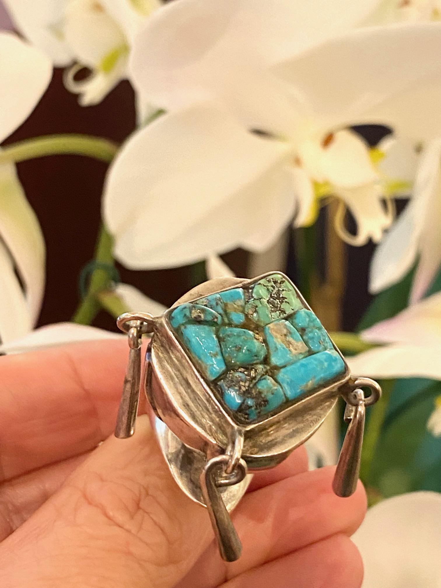 A unique turquoise and sterling silver ring with articulated parts, by Eveli Sabatie, United States, circa 1970. Signed Eveli. Ring size 5.25. This ring can be sized one size. 
Ring measures 1.25