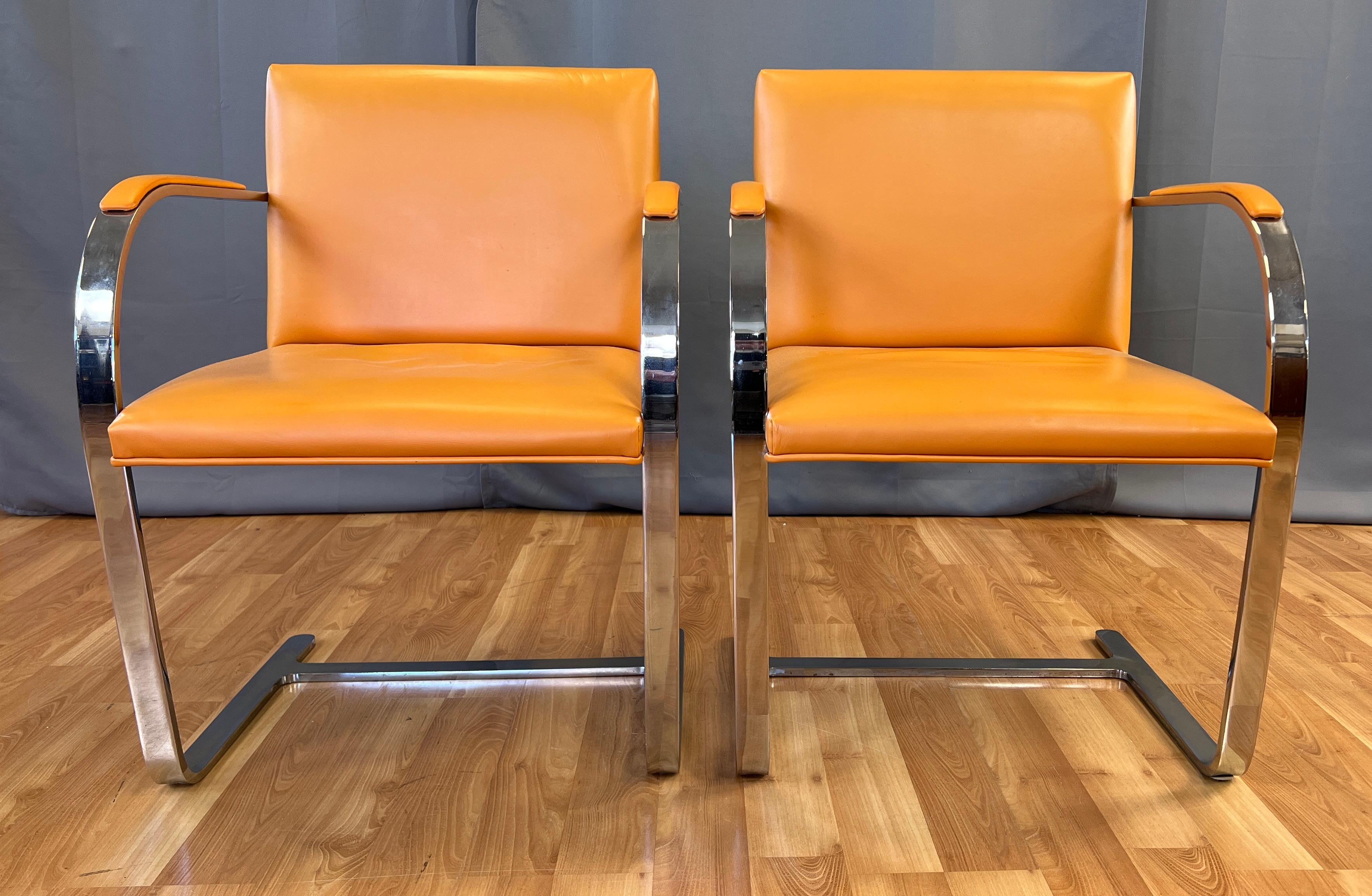 Two wonderful circa 1970s flat bar Brno armchairs in orange leather, designed by Mies Van der Rohe. 
Made by Gordon International, in the country of Argentina. 
The chairs are a Classic design, with a great splash of color with their orange