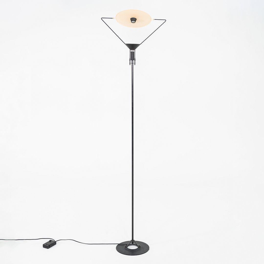 This is a Polifemo floor lamp, originally designed by Carlo Forcolini in 1983. This particular example was produced by Artemide in Italy in the 1980s. The lamp's design is comprised of disk diffuser with a mirror halogen reflector atop a metal body