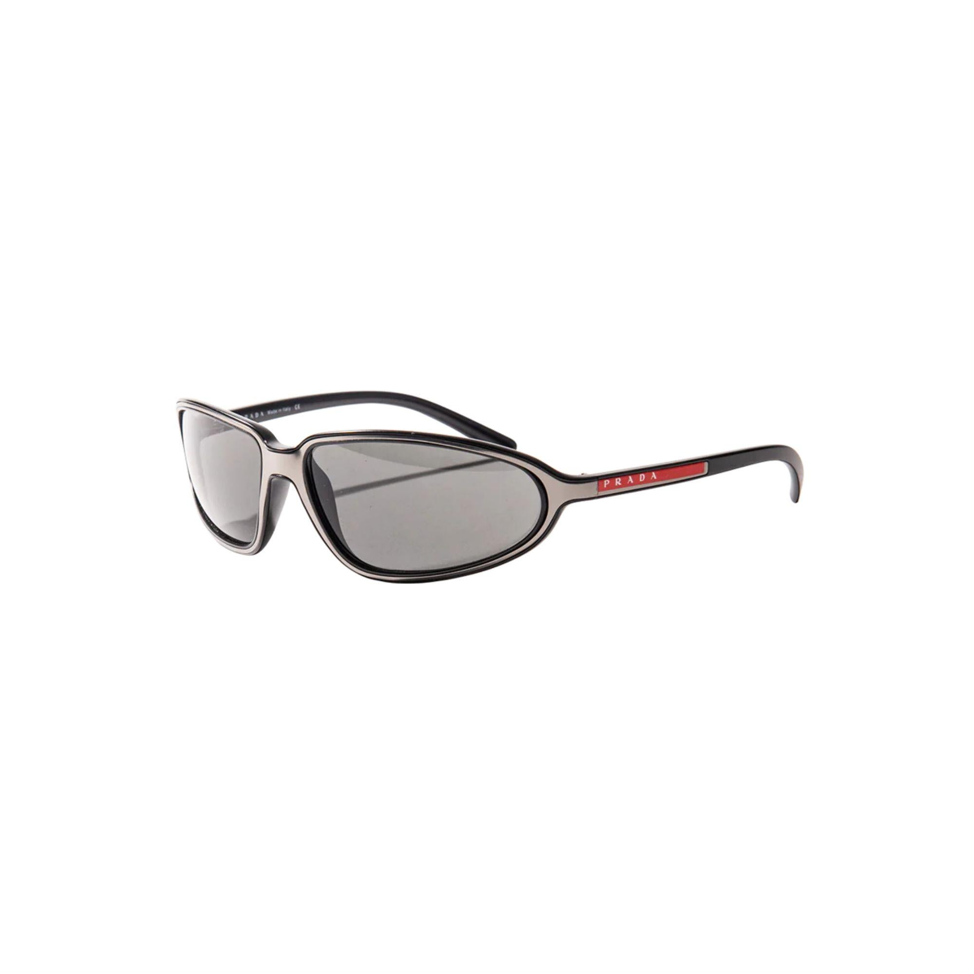 c. 1999 Prada black and silver sunglasses. Black frame sunglasses with metallic silver overlay throughout and red Prada logo on side. As seen on Brad Pitt throughout many iconic moments in the 1990s and early 2000's. One size fits all (mid-sized