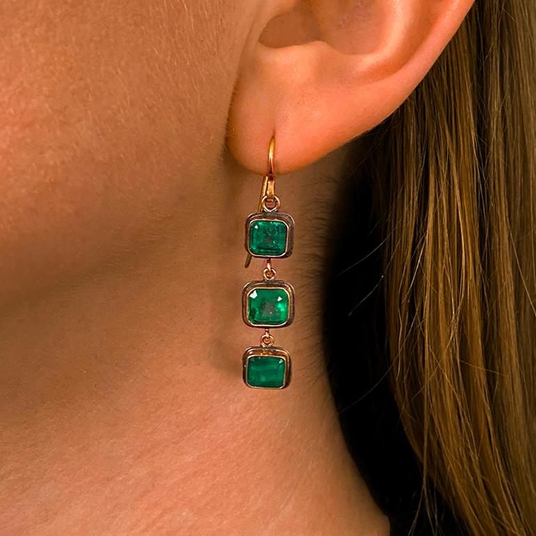A pair of hand made, stylish emerald, oxidized sterling silver and 18 karat gold earrings, by Judy Geib c.2010. The earrings are both signed with Judy Geib's maker's mark and feature wire fixtures for pierced ears. Six emerald cut emeralds total to