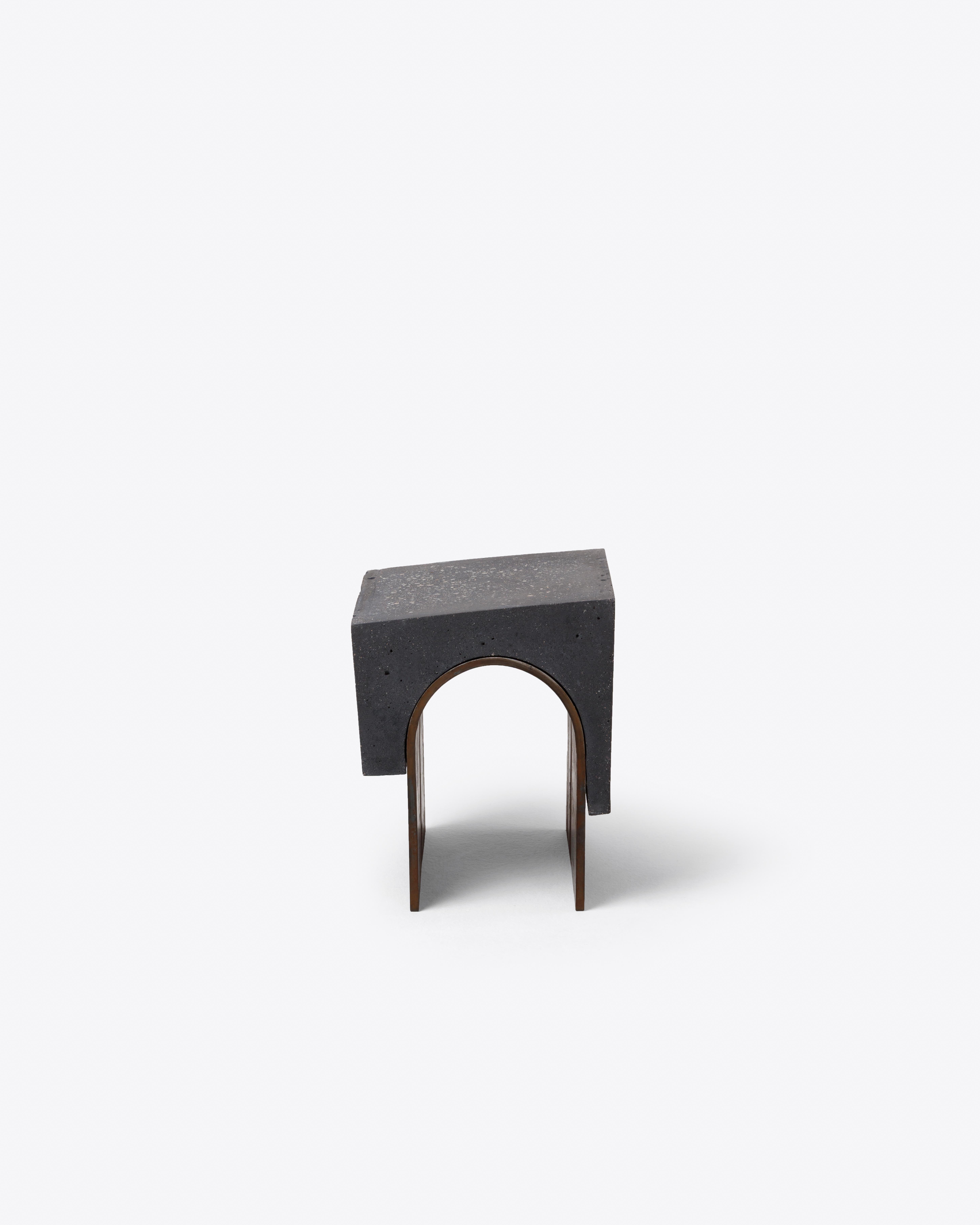 This side table combines black concrete with an arched steel base, echoing the compositional strategy of its rosé
counterpart but in a more elemental, grounded tone. Its formal logic recalls Brutalist architecture, distilled into a
precise and