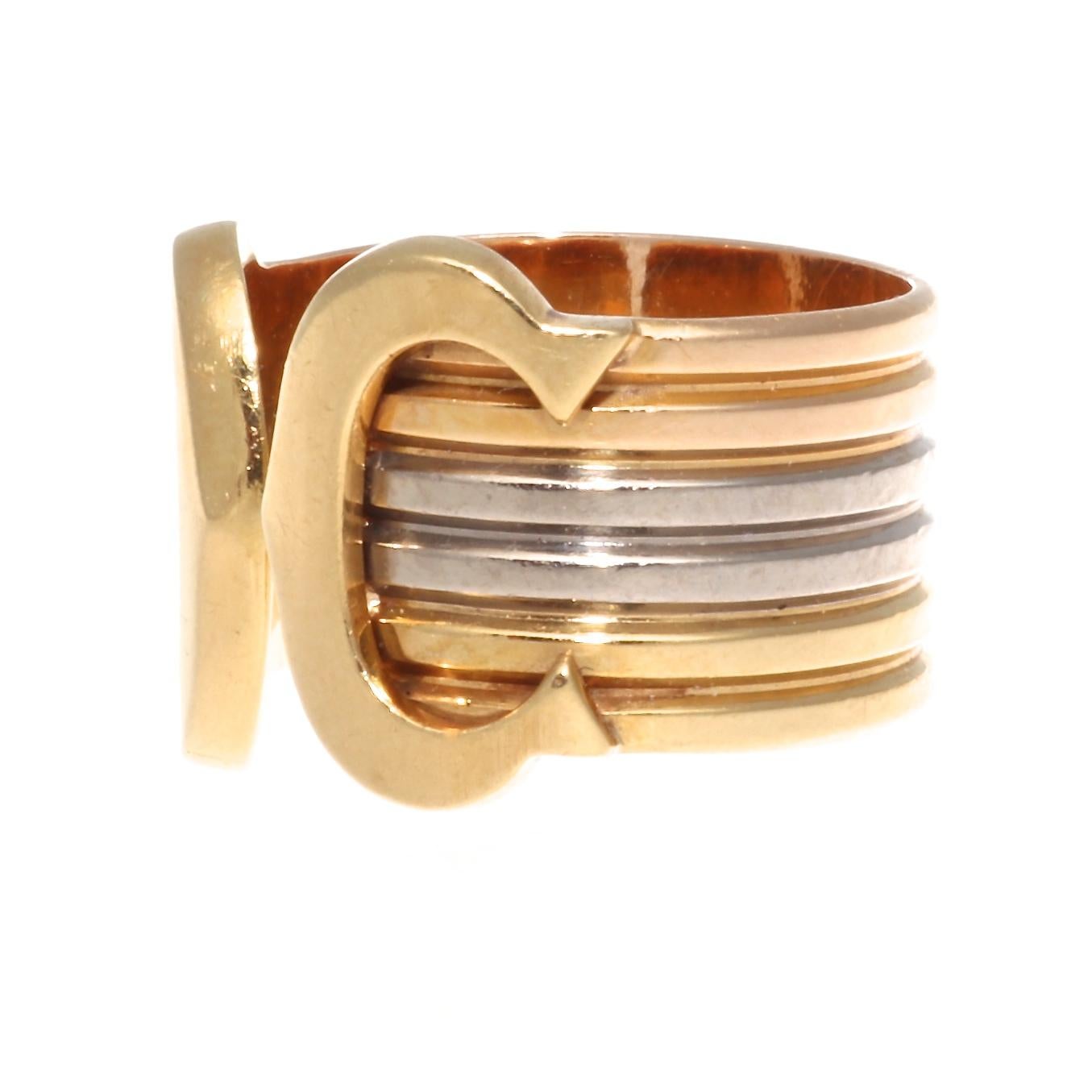 Cartier signature C ring is pure elegance. A discreet initial of unique purity. Featuring C's of yellow gold wrapped in a tricolor gold band. Signed Cartier, serial number. Ring size 49 or 4-3/4.