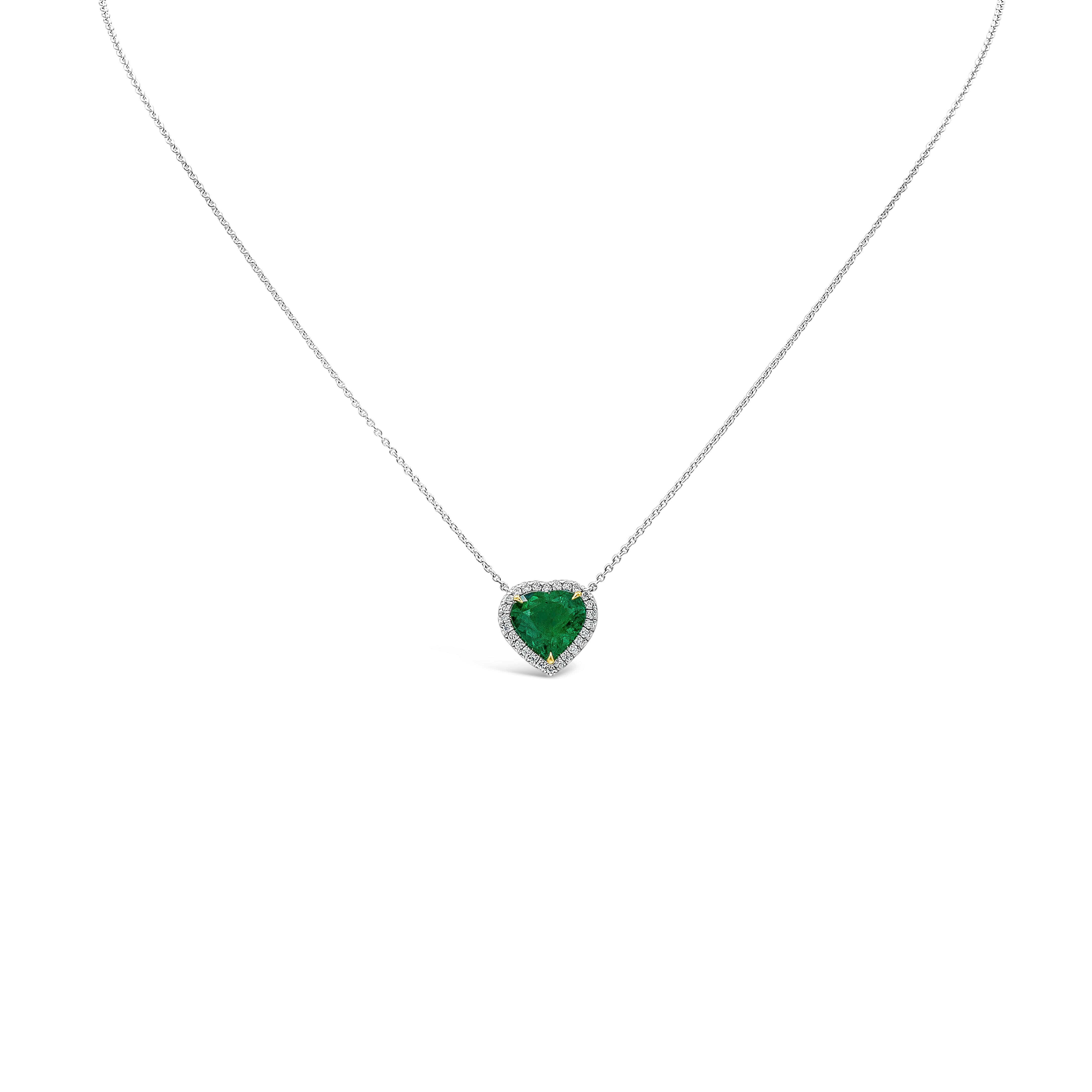 A rare piece of jewelry showcasing a C. Dunaigre Certified 2.33 carat colombian vivid green emerald in a heart shape, VS in Clarity. Surrounded by a single row of round brilliant diamonds weighing 0.21 carats total, F Color and VS in Clarity. having