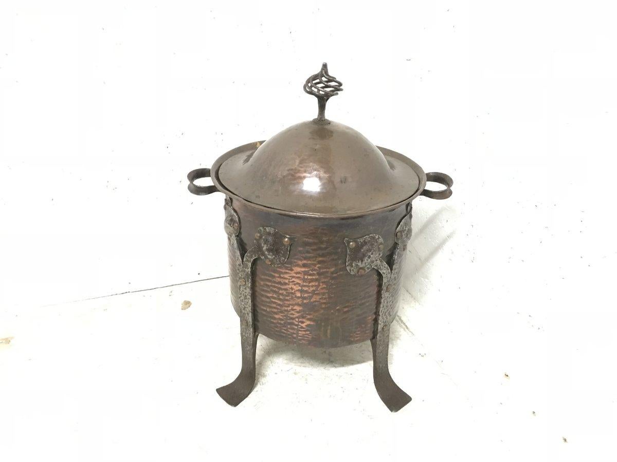 In the style of C F A Voysey.
An Arts & Crafts copper coal bucket with Hand-formed stylized floral decorative iron work details and wire work finial.

Dimensions:
Height - 21