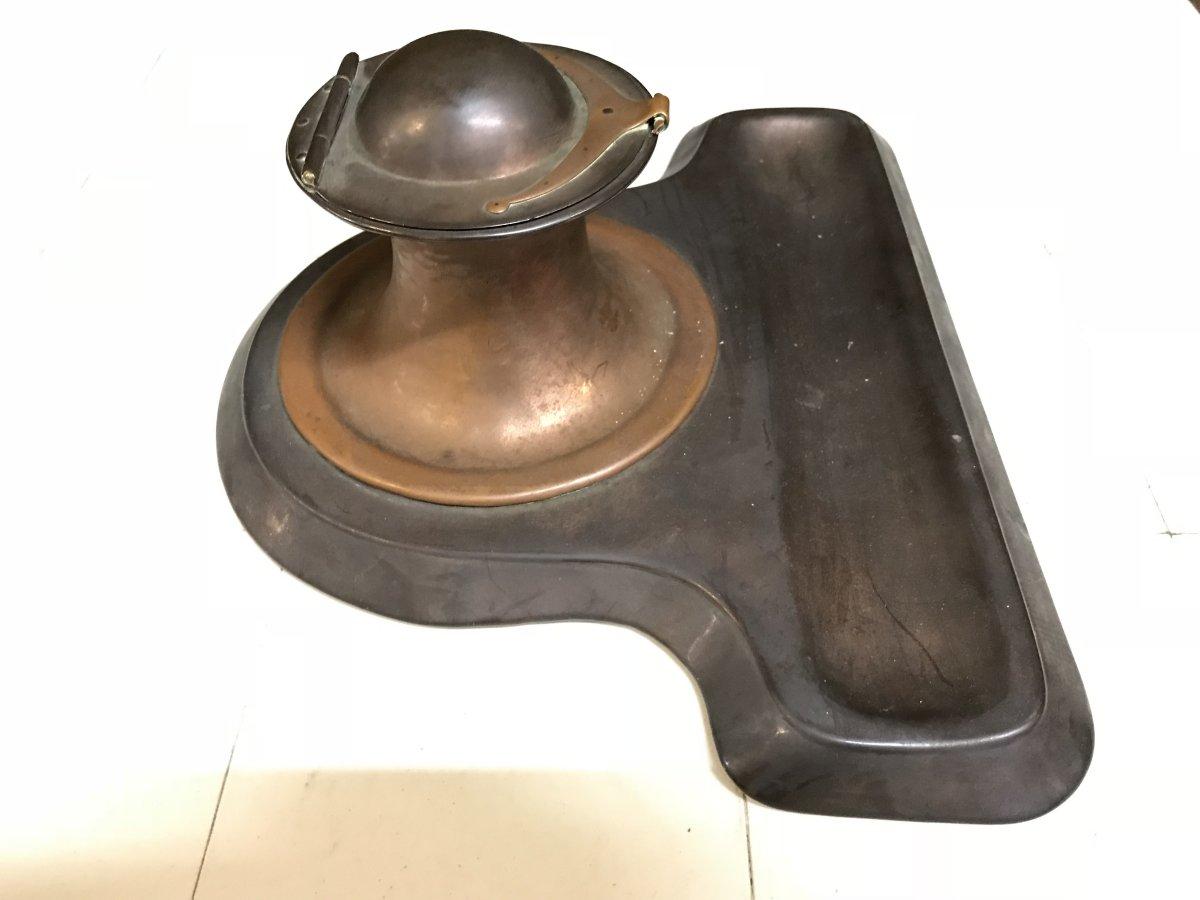 C F A Voysey attributed. Made by Richard Rathbone, stamped maker to the base.
An Arts & Crafts copper inkstand with domed top lid with upturned lip handle and a pen tray to the front.
 