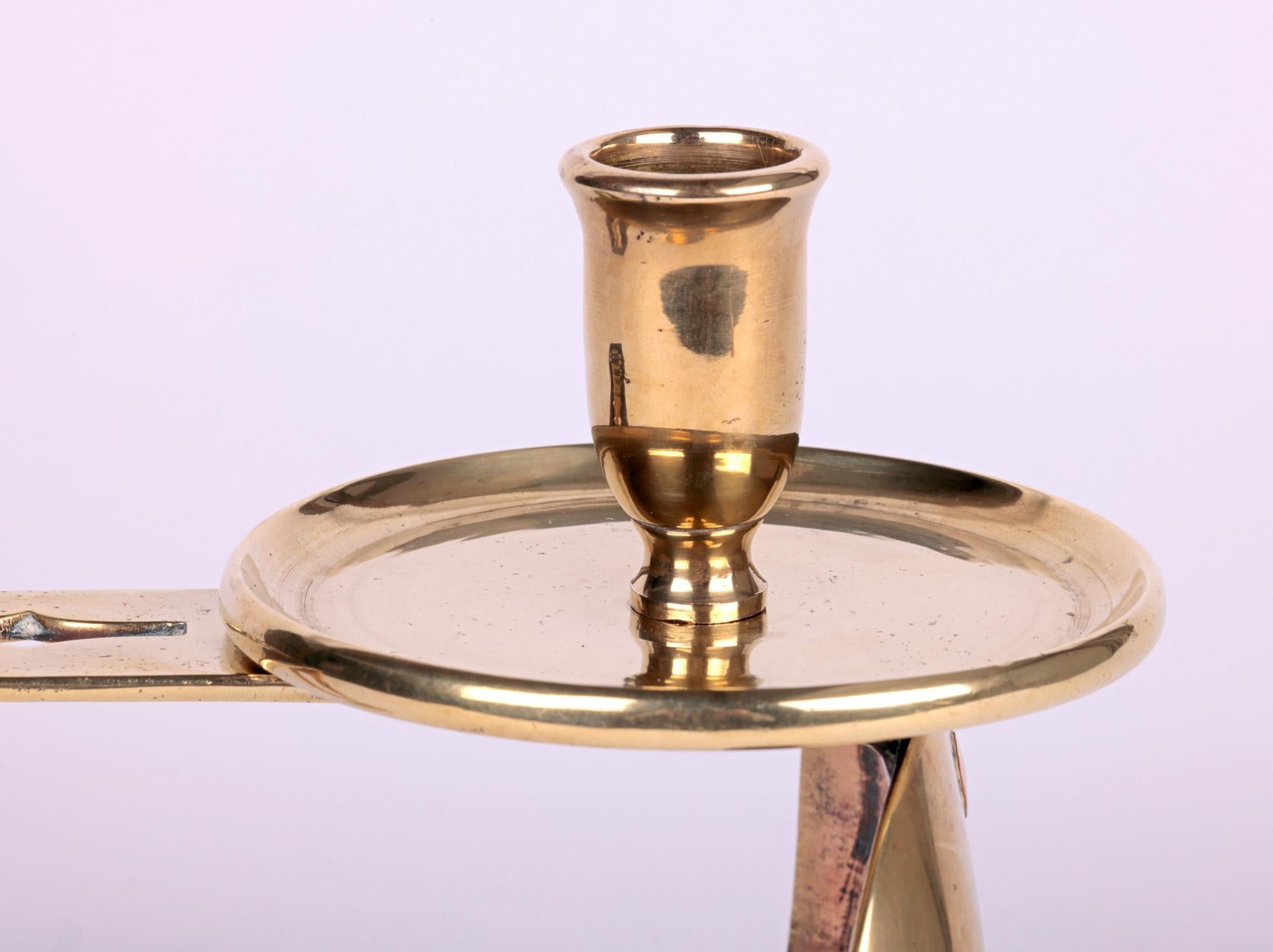 An unusual Arts & Crafts brass chamberstick attributed to C.F.A. Voysey and made by Edward Barnard & Son with date marks for 1910. This stylish and heavily made Edwardian brass chamberstick has a wide round top with raised central candle holder and