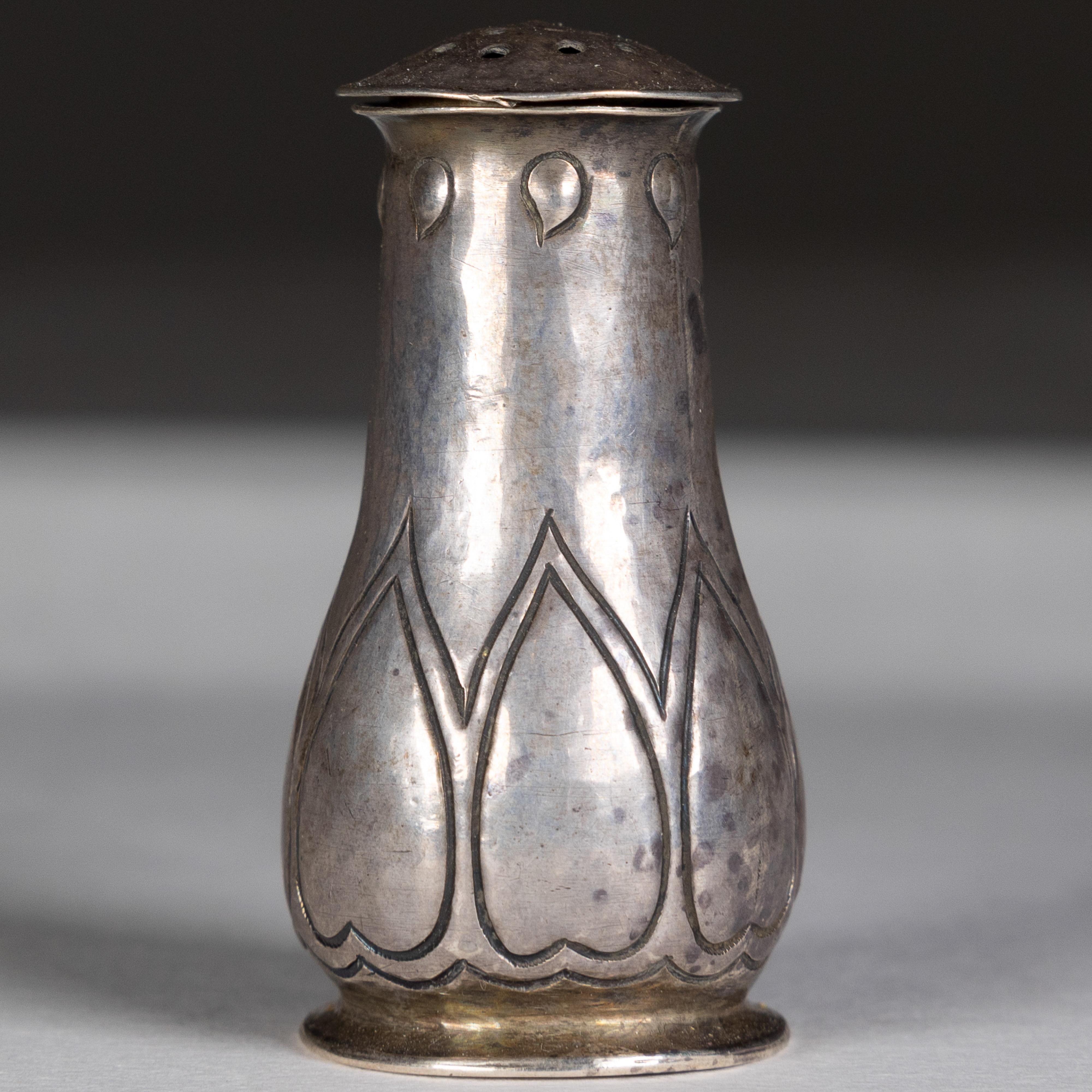 C.F.A. Voysey attributed. 
Made by the Keswick School of Industrial Art.
An Arts and Crafts silver salt shaker
Handmade with stylized heart decoration, with a pierced removable lid. Stamped maker’s and hallmarks K.S.I.A. Chester, Circa