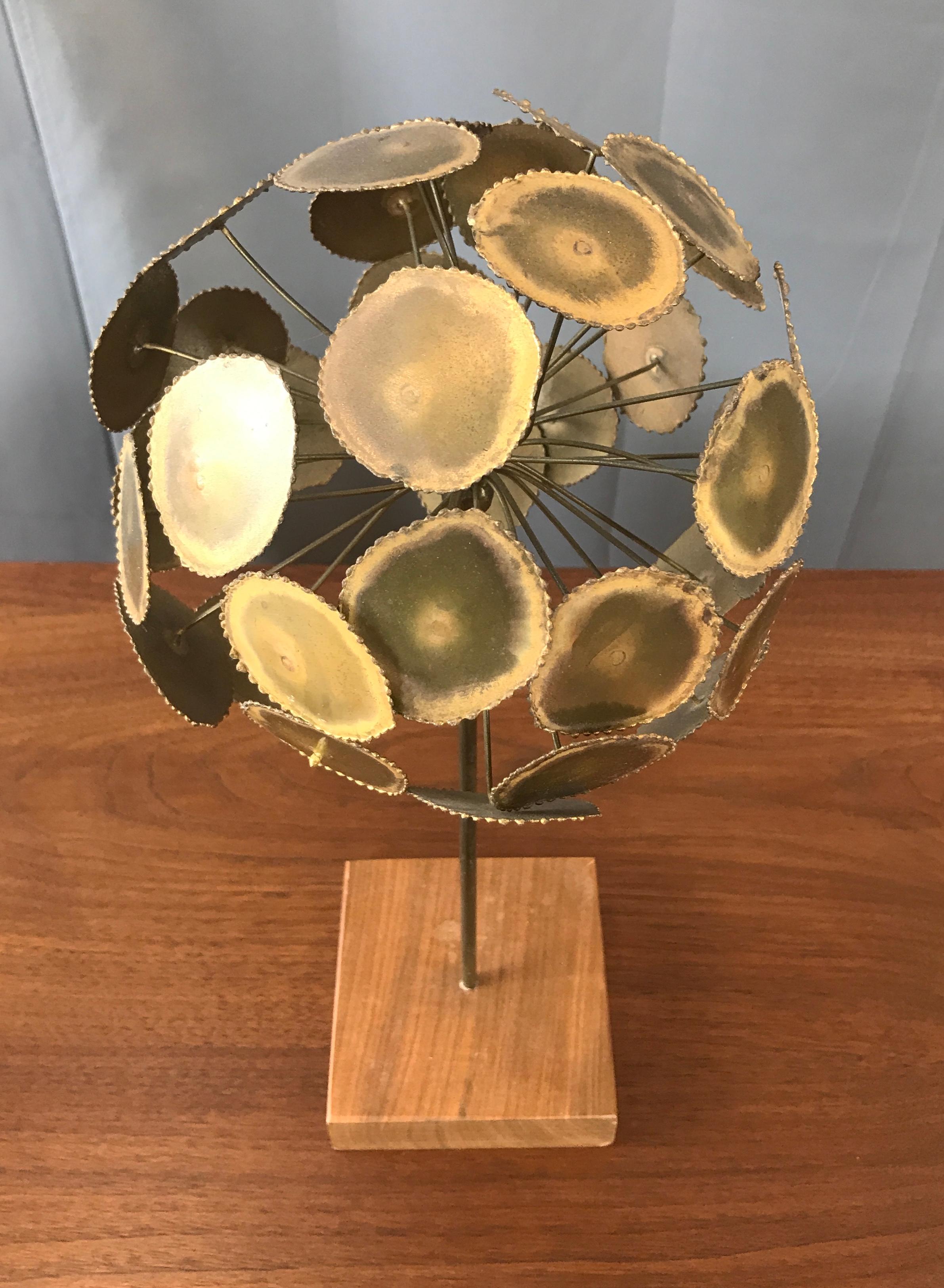 A mounted Brutalist sculpture attributed to Curtis Jere, Artisan House (no signature found). Walnut base with a single brass pole reaching up, with an explosion of brass disks.

Measures: Base is 4.50 x 4.50.