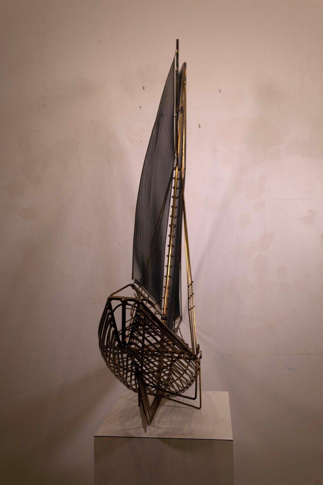 This mid-century modern sculpture by C. Jere is a stylized representation of a sailboat, crafted from golden metal, capturing the elegance and simplicity of nautical design. The piece is signed by the artist, dating to 1982, and features slender