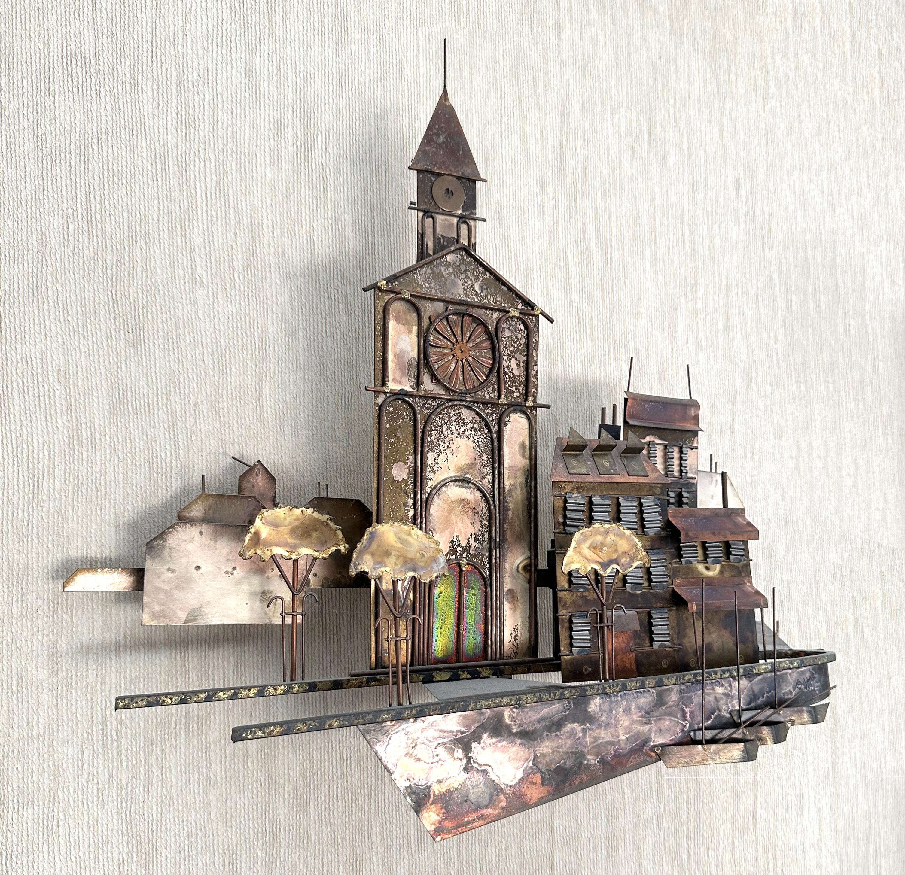 Designed by Curtis Jeré - a collective pseudonym for artists Curtis Freiler and Jerry Fels - this signed “C. Jeré” wall sculpture was produced by their company, Artisan House, in 1972.

A charming and whimsical village scene, it features a church,