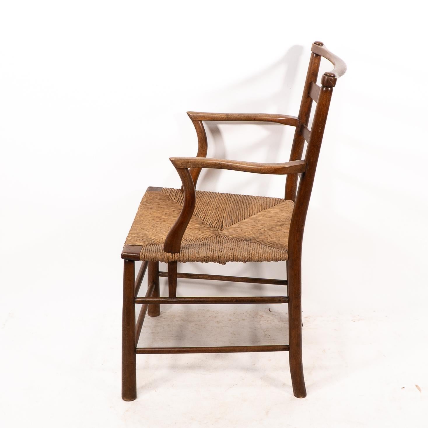 Late 19th Century C R Ashbee. An Arts and Crafts rush seat ladder back armchair For Sale