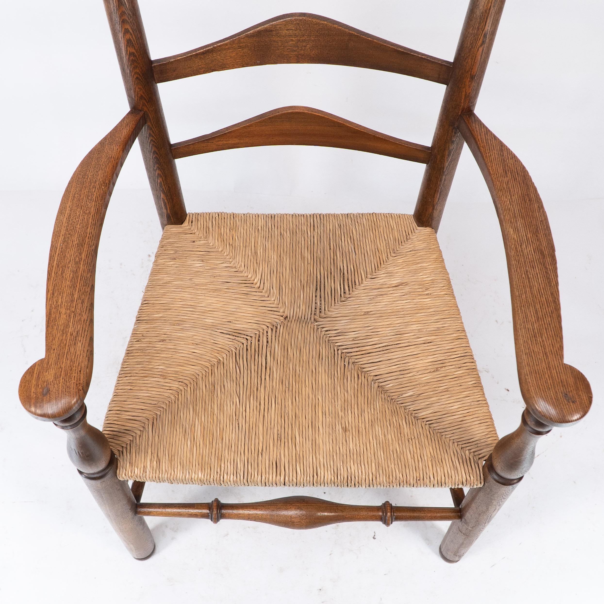 Rush C R Ashbee attr. An Arts & Crafts oak ladder back armchair with re-rushed seat For Sale