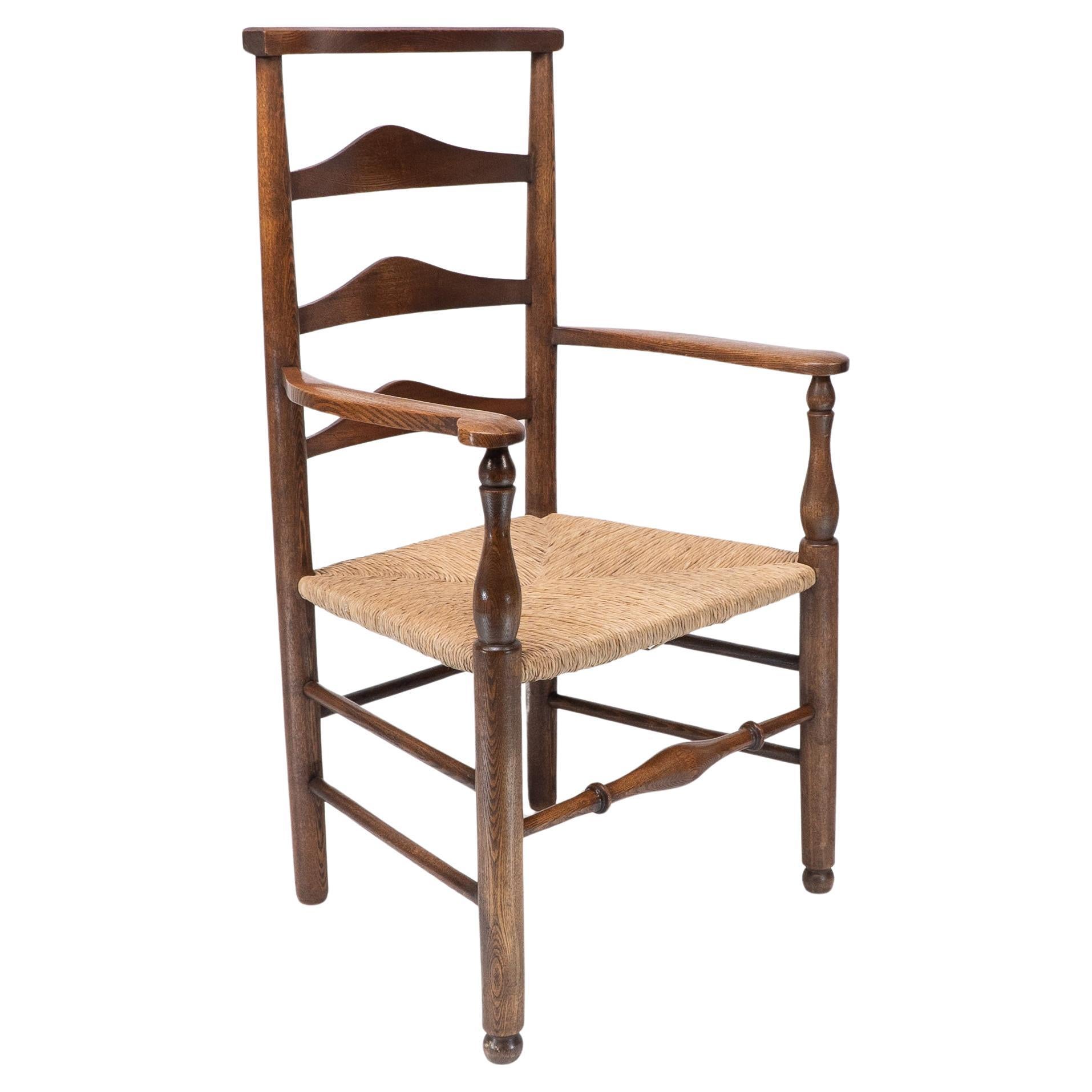 C R Ashbee attr. An Arts & Crafts oak ladder back armchair with re-rushed seat For Sale