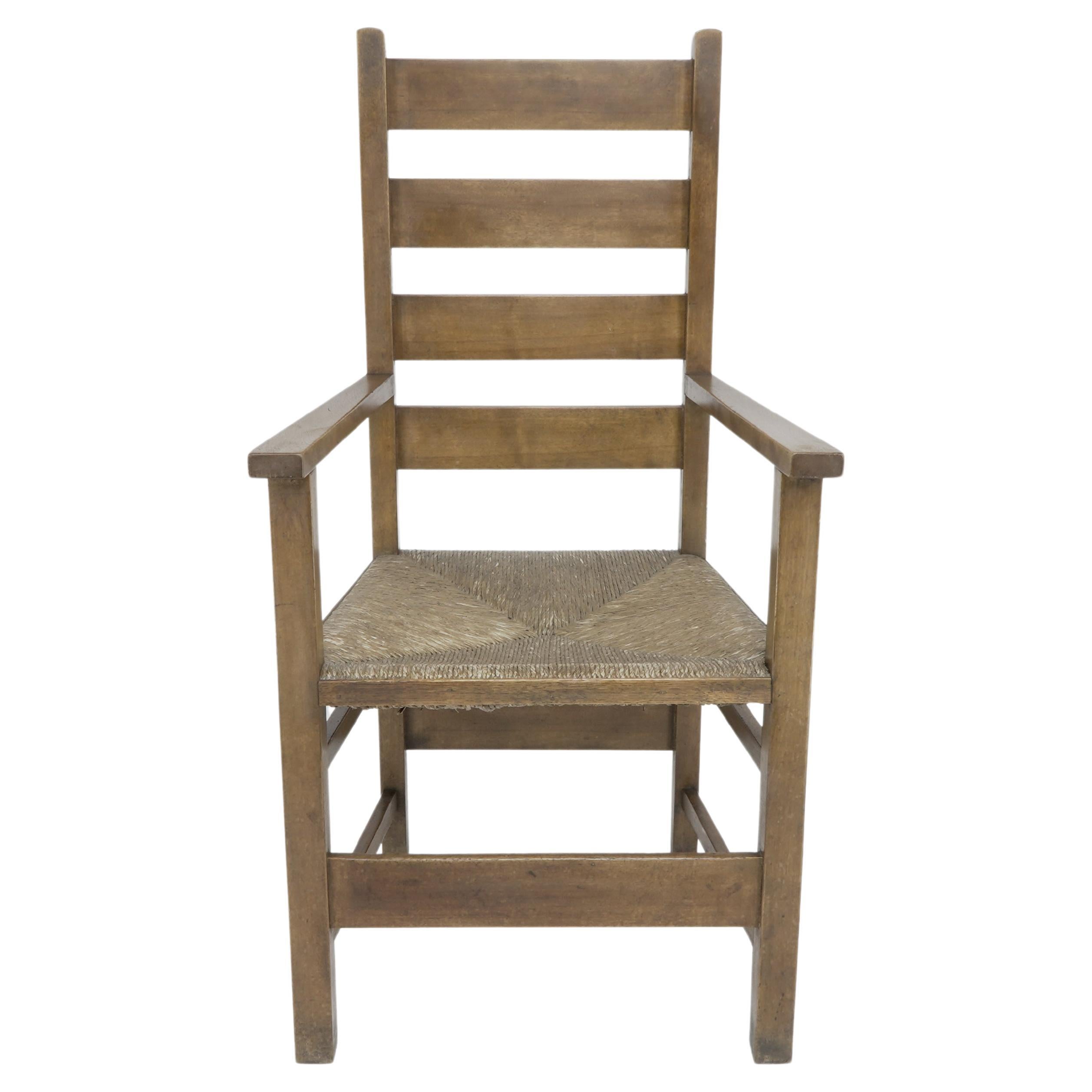 M H Baillie Scott. An Arts and Crafts oak and rush seat ladder back armchair made by J P White at The Pyghtle Works in Bedford. Illustrated in: Furniture made at The Pyghtle Works Bedford by J P White. Designed by M H Baillie Scott, Fig No 8.

