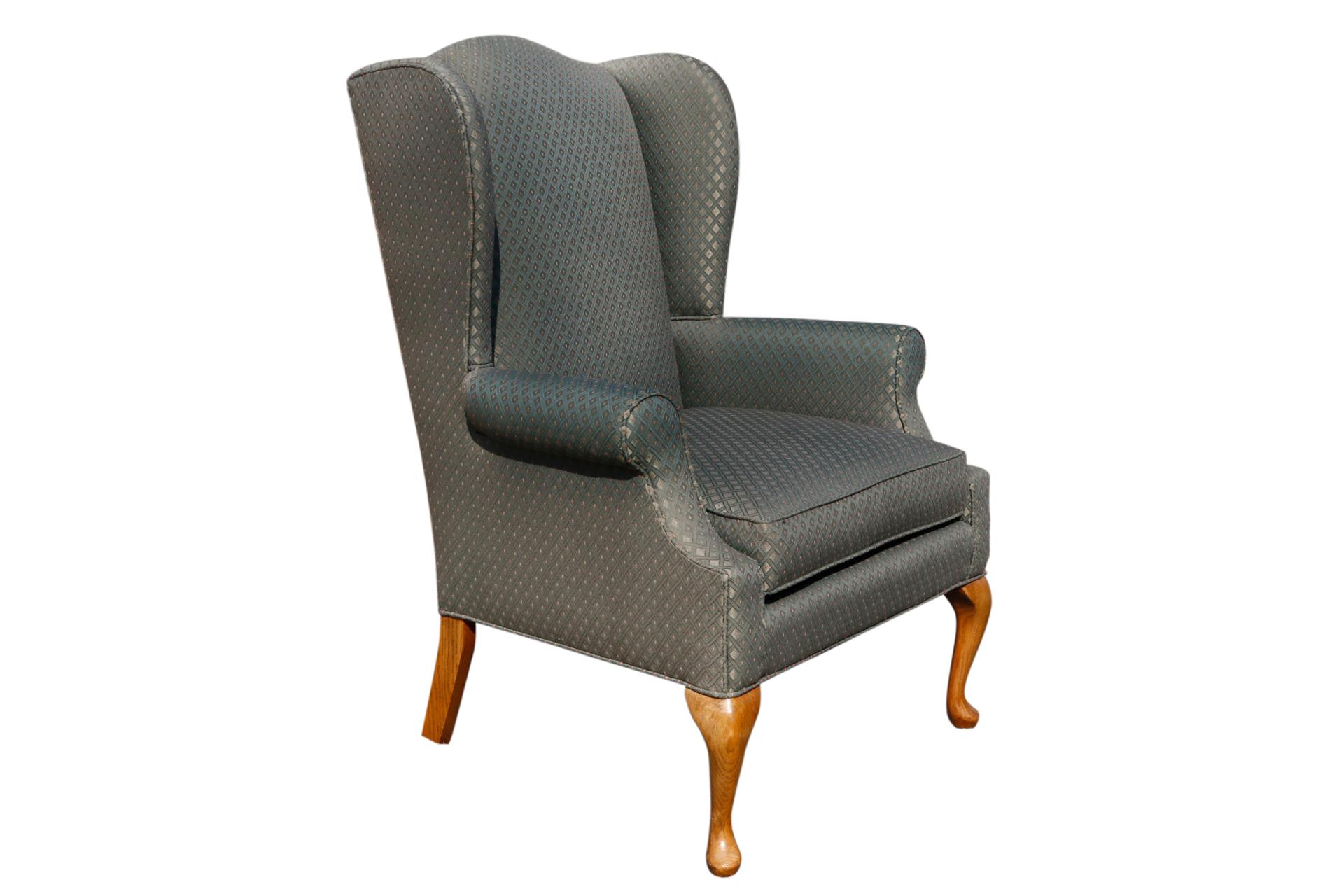 A pair of Queen Anne style wingback chairs made by C.R. Laine for their Carolina collection. Upholstered throughout in an green jacquard fabric with a diamond motif. Cabriole legs finish in rounded pad feet. Arm height 25