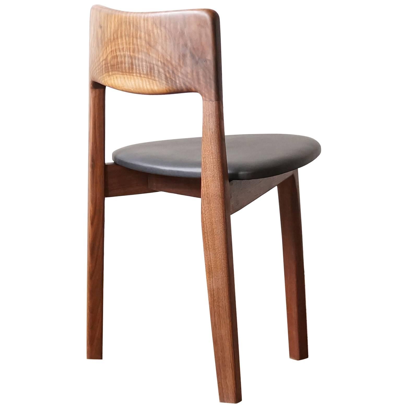 The C11 chair is a three-legged solid hardwood side chair, meant to pair perfectly with our round T08 table but with a unique sculptural presence on its own as well. The angled back legs and the hand shaped seat back are oriented so that they