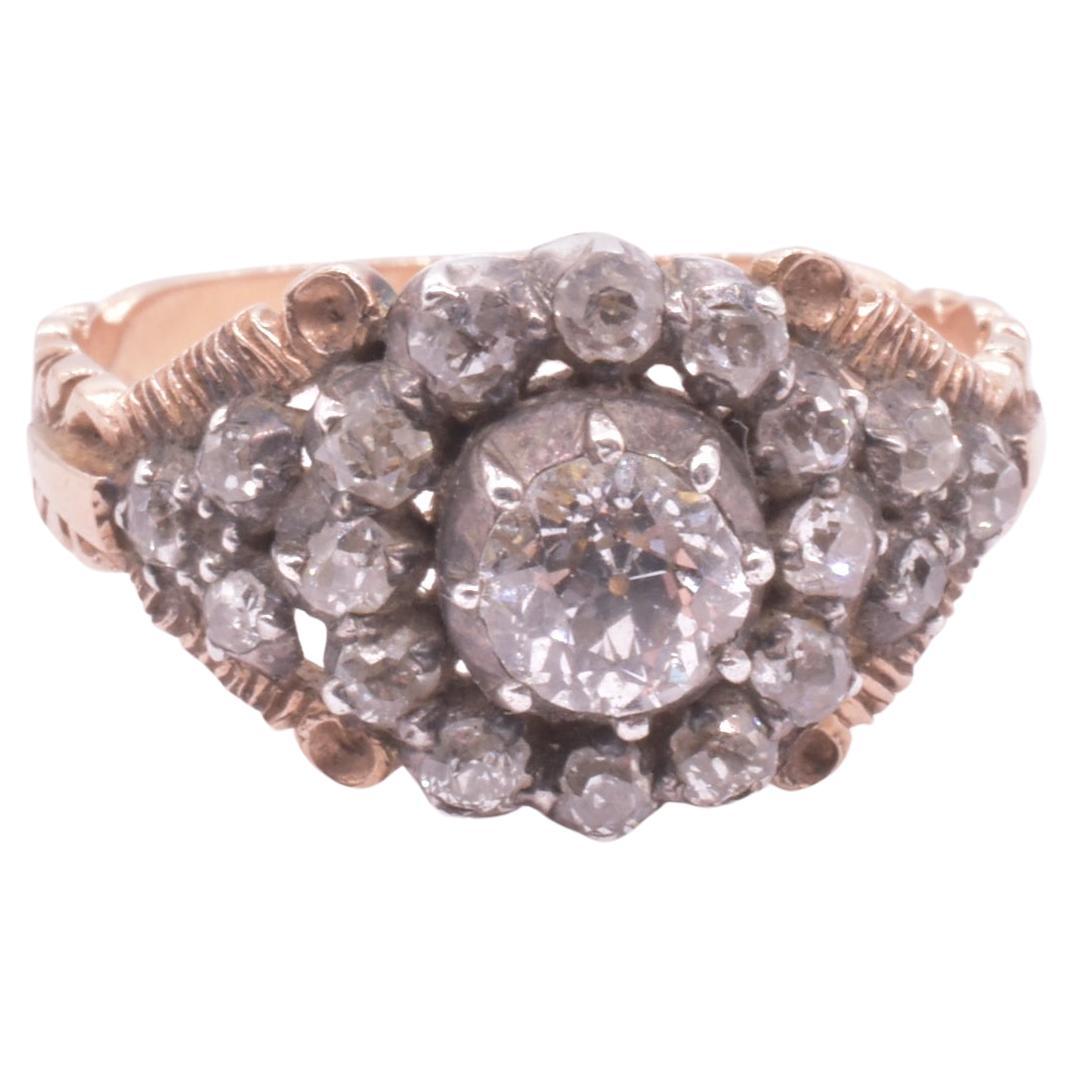 Impressive Georgian diamond cluster ring with nineteen diamonds in a silver setting with an 18K delicately incised and unusually shaped gold band dating to c. 1780. The pictures speak for themselves. 

The ring is oriented around a large central
