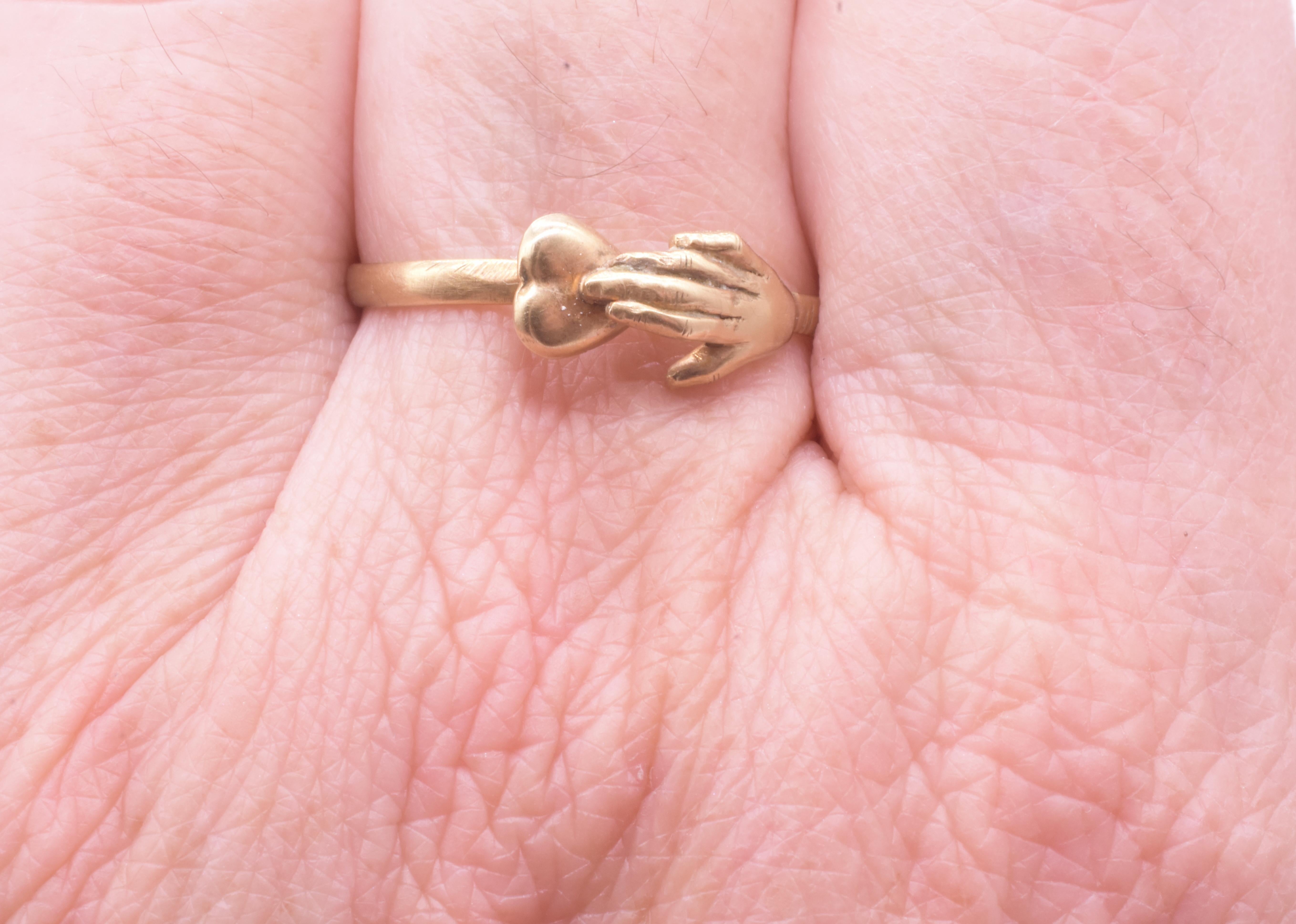 Our 18K rare fede ring has a delicately carved hand gently touching a heart with the symbolizing  